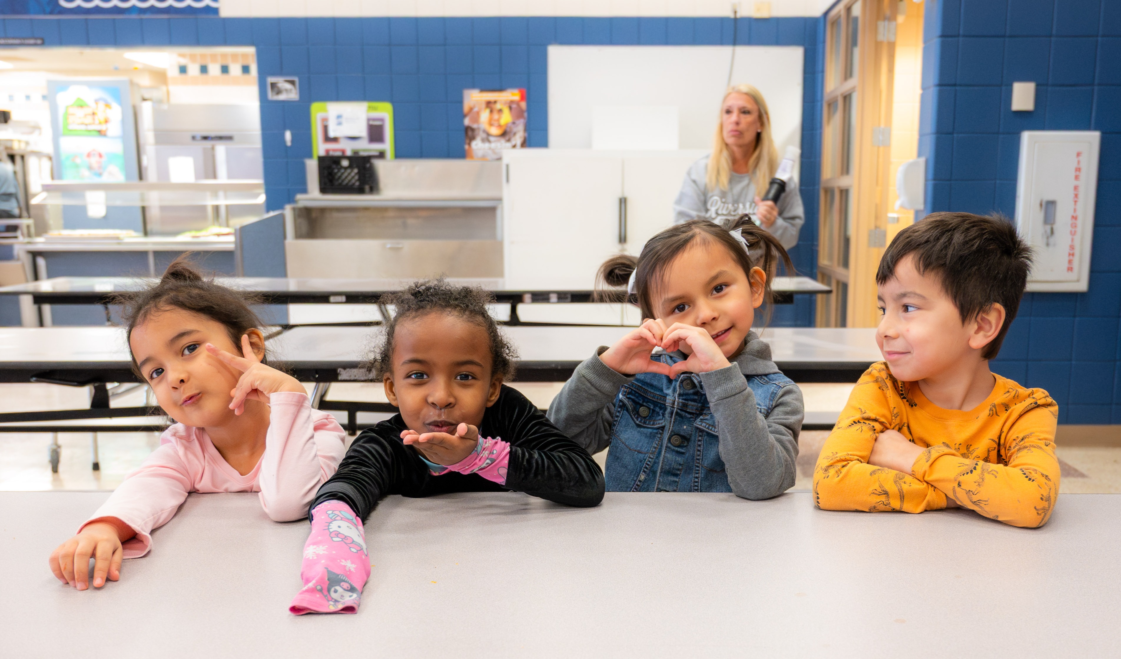 Four kids sit at a lunch table and pose in the most charming ways!