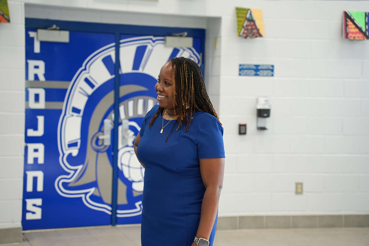 A woman in a blue dress stands in front of a blue door with a logo.