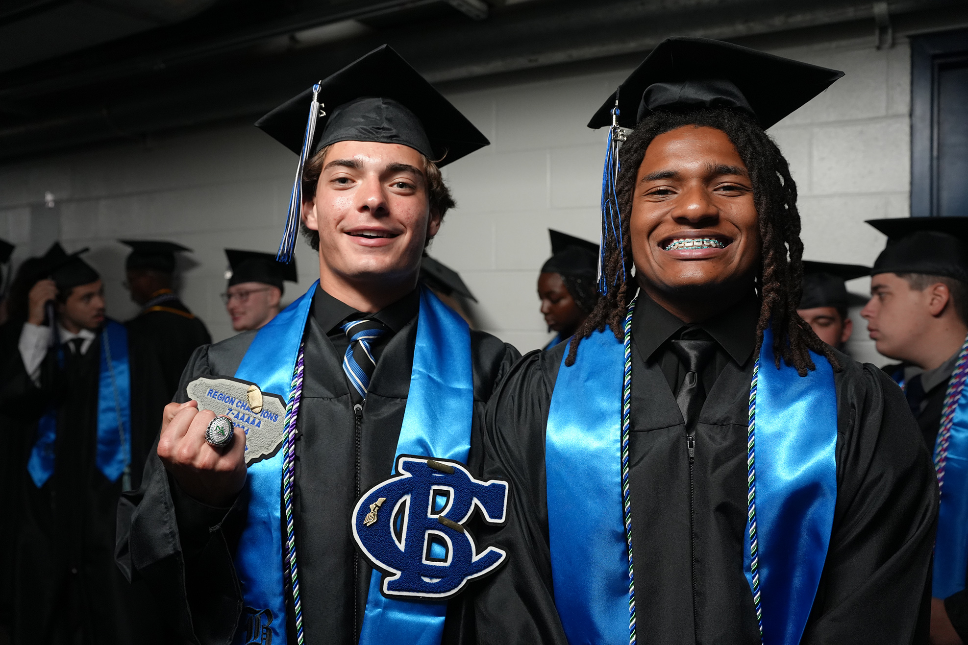 Two men in blue stoles and graduation gowns stand side by side, smiling and posing for a photo.
