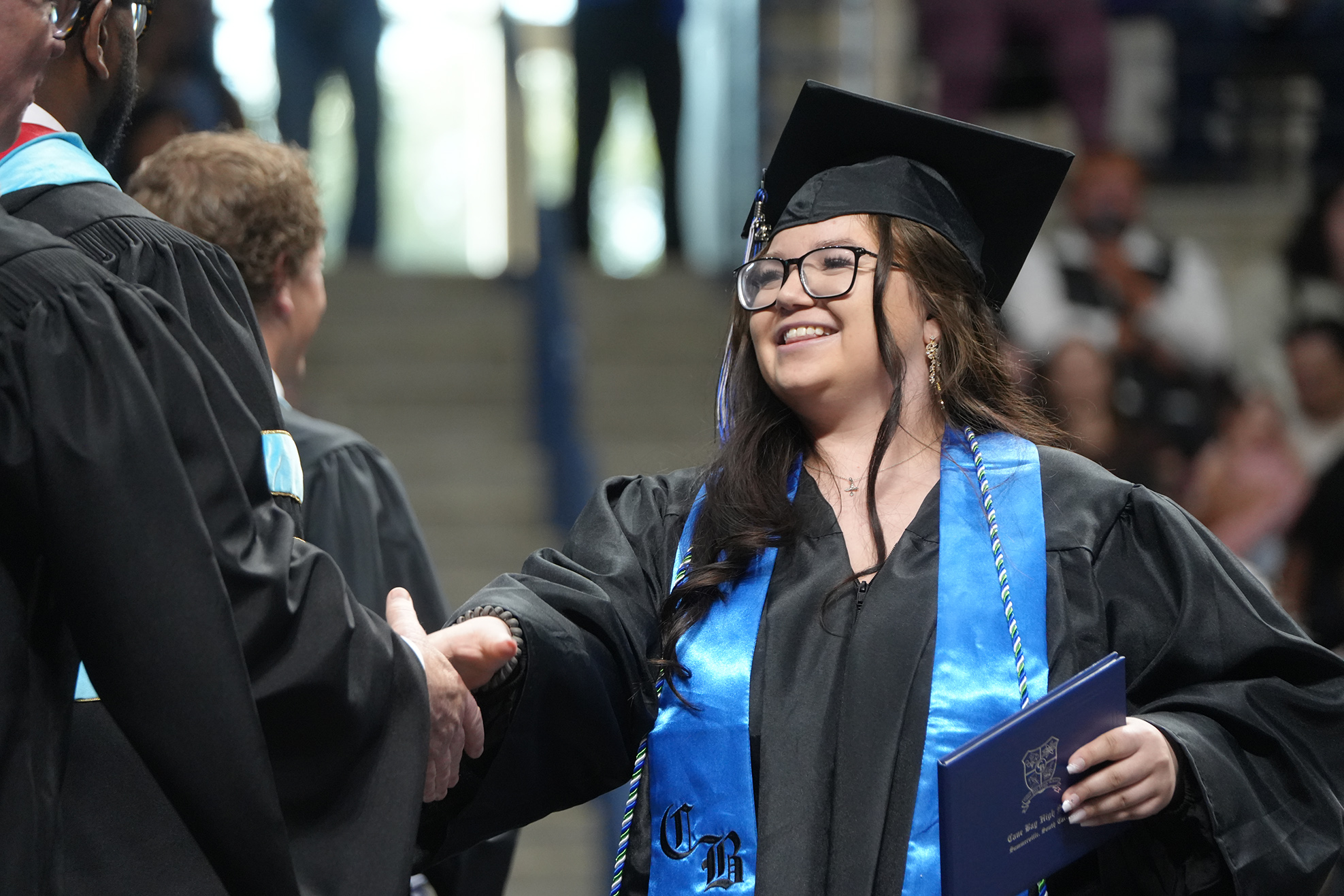 A person in a graduation gown shakes hands with an official at a ceremony.