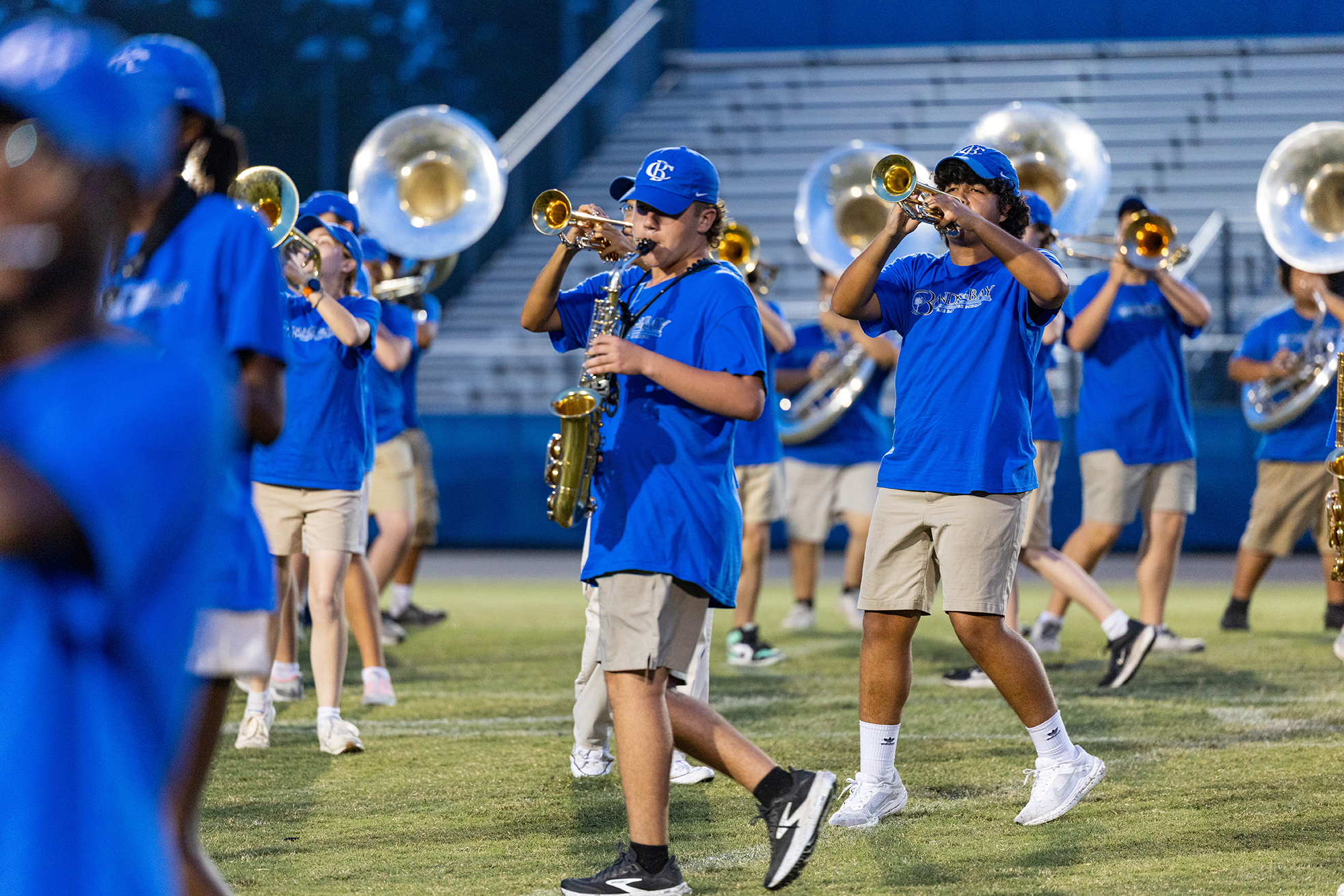 A marching band on a field. Some members are playing instruments while others are standing in a row.