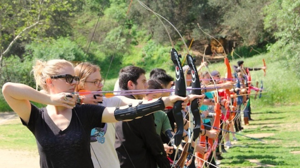 photo of students in a line holding bow and arrow up