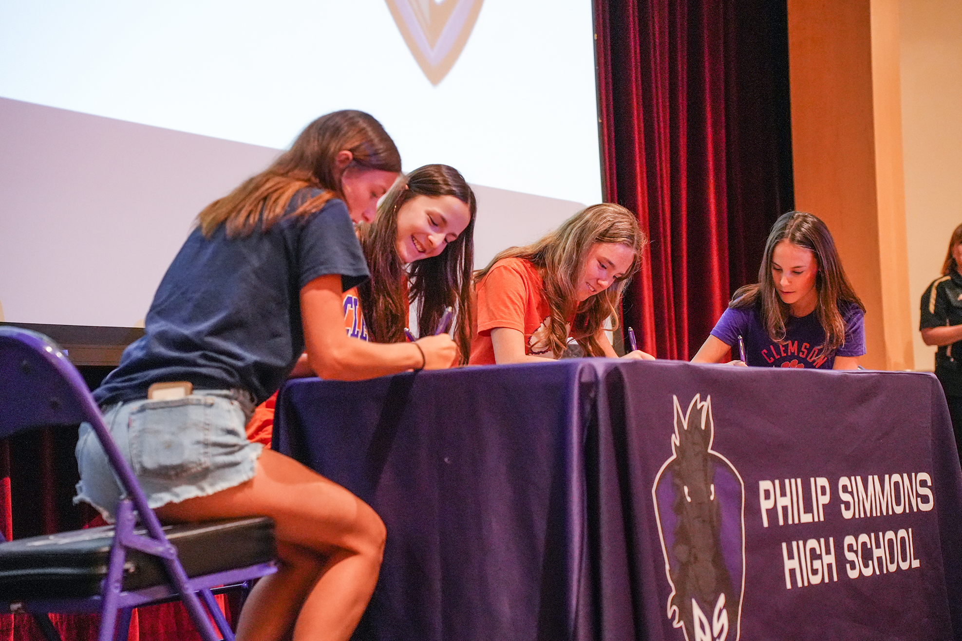Five students seated around a table with a banner reading "Philip Simmons High School," signing documents.