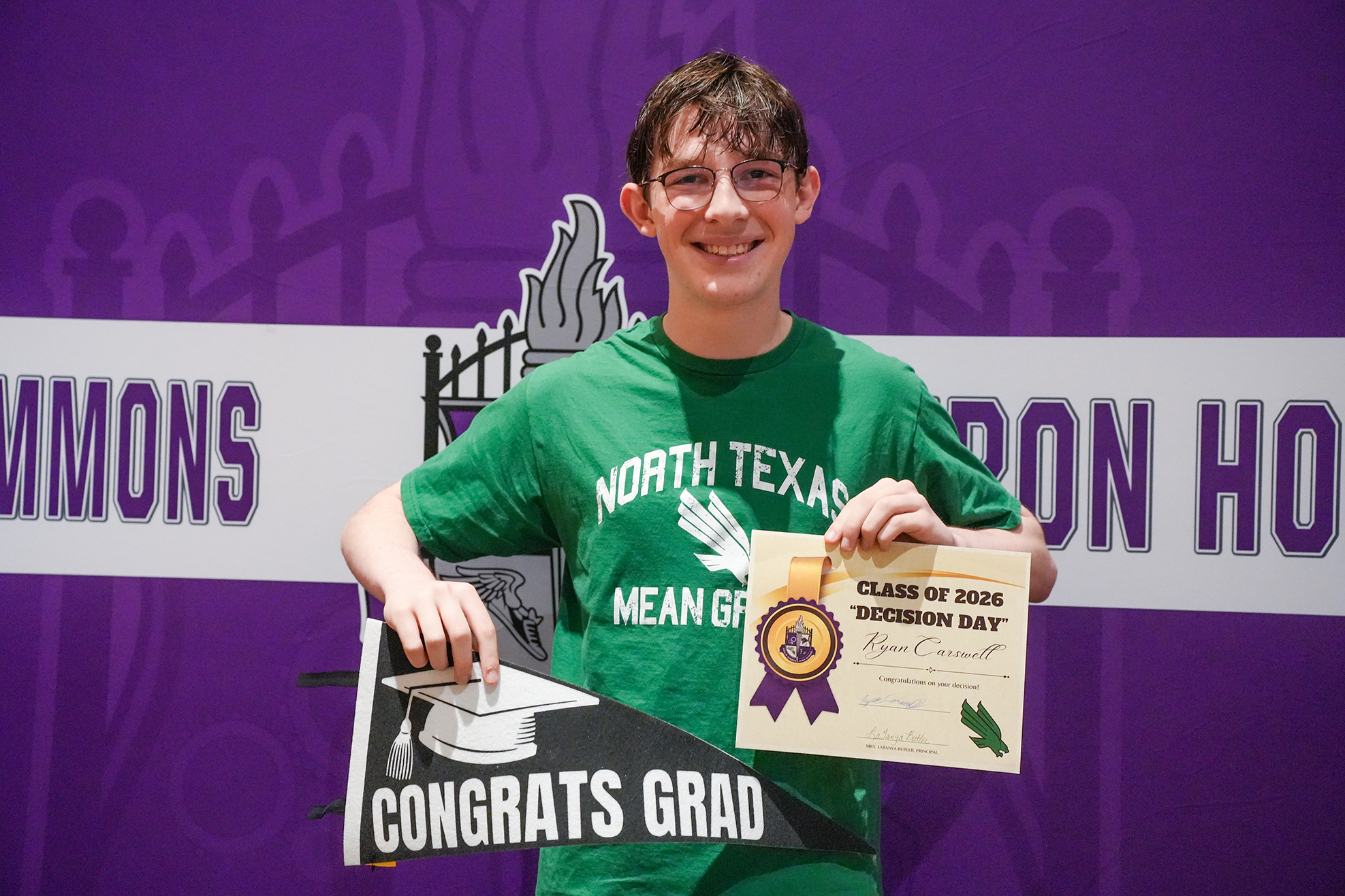 A young man holds a graduation cap and certificate against a purple backdrop with the text "COMMONS" and "HON HO".