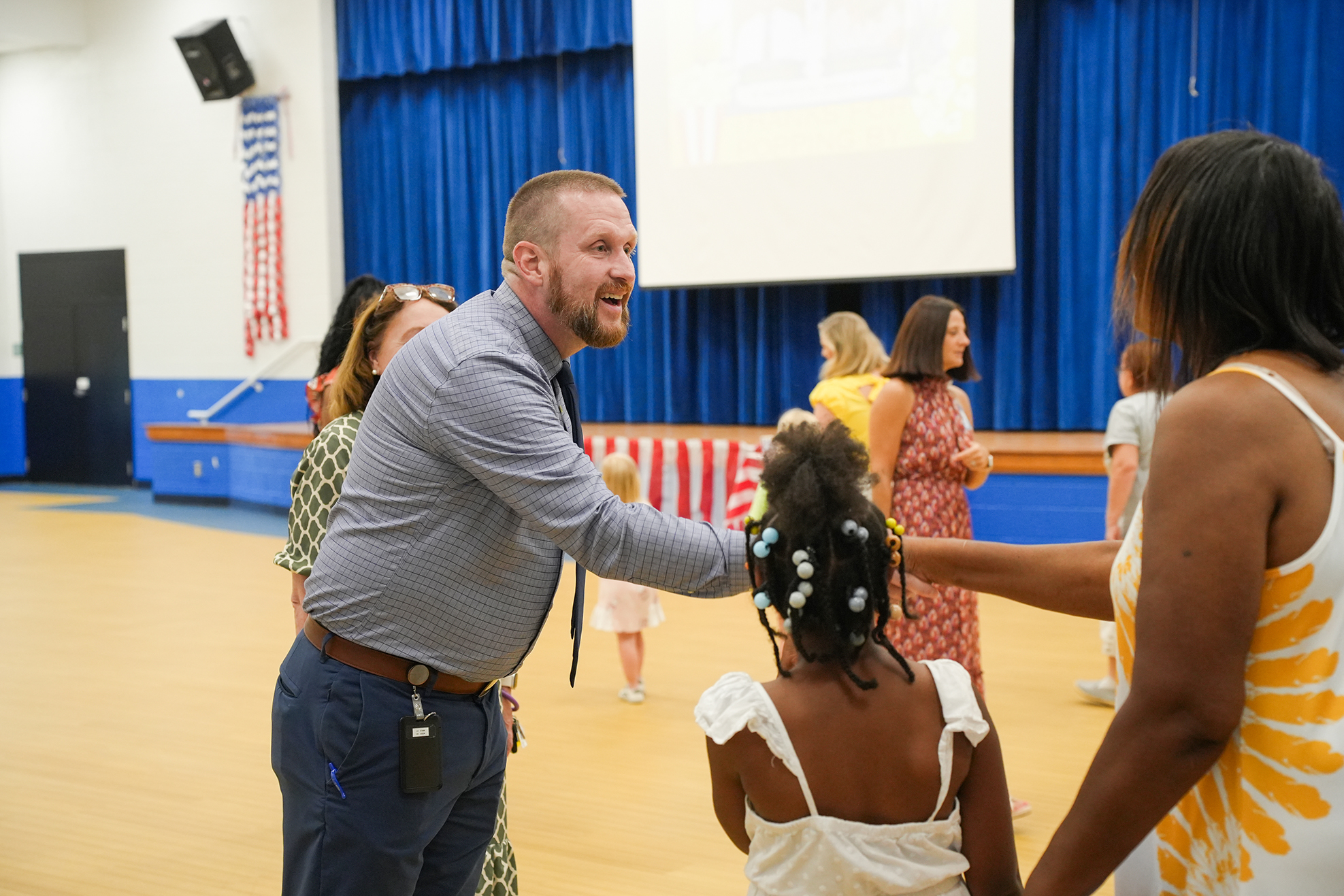 A man, two women, and a young girl in a gym. The man and women hold hands.