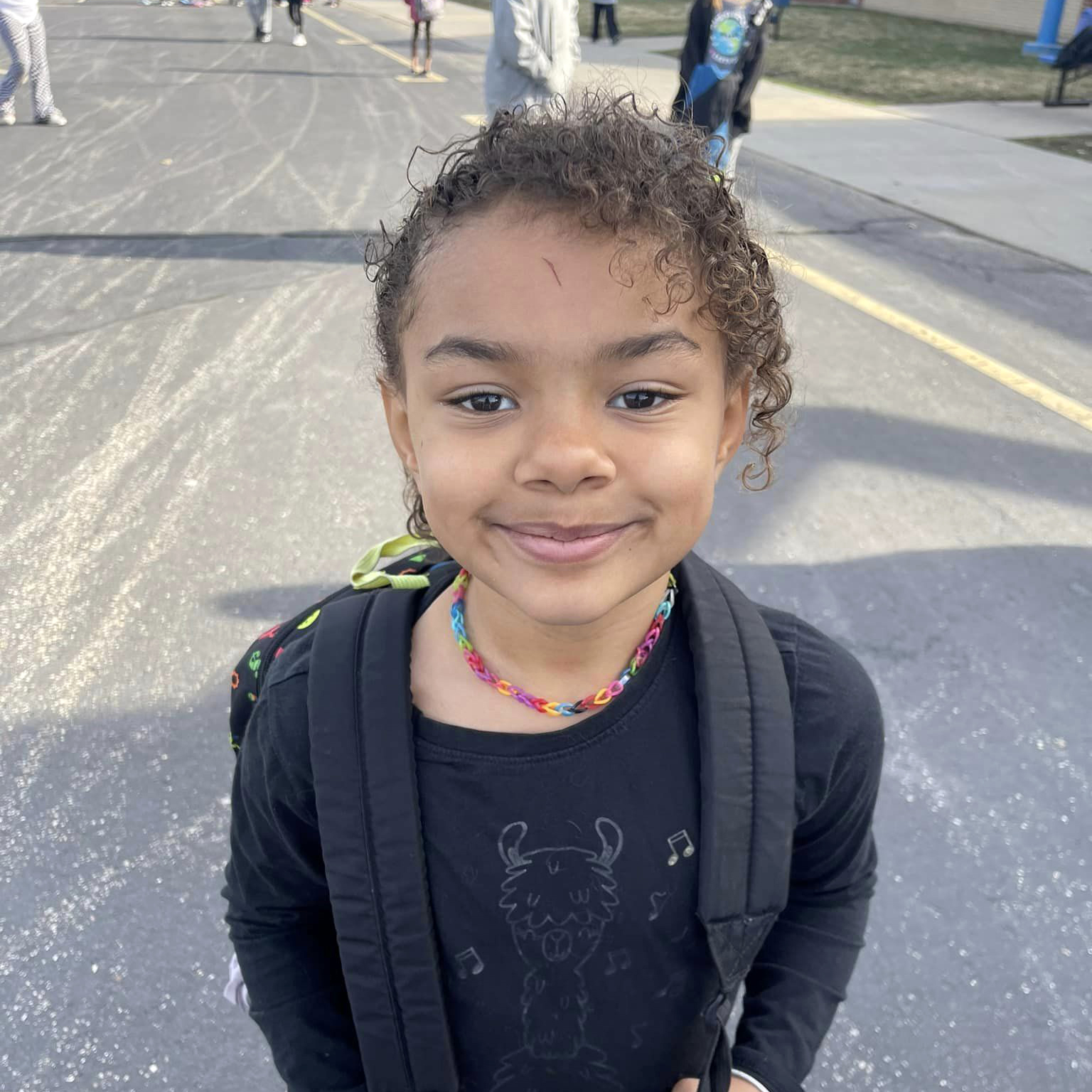 A student standing outside, smiling at the camera