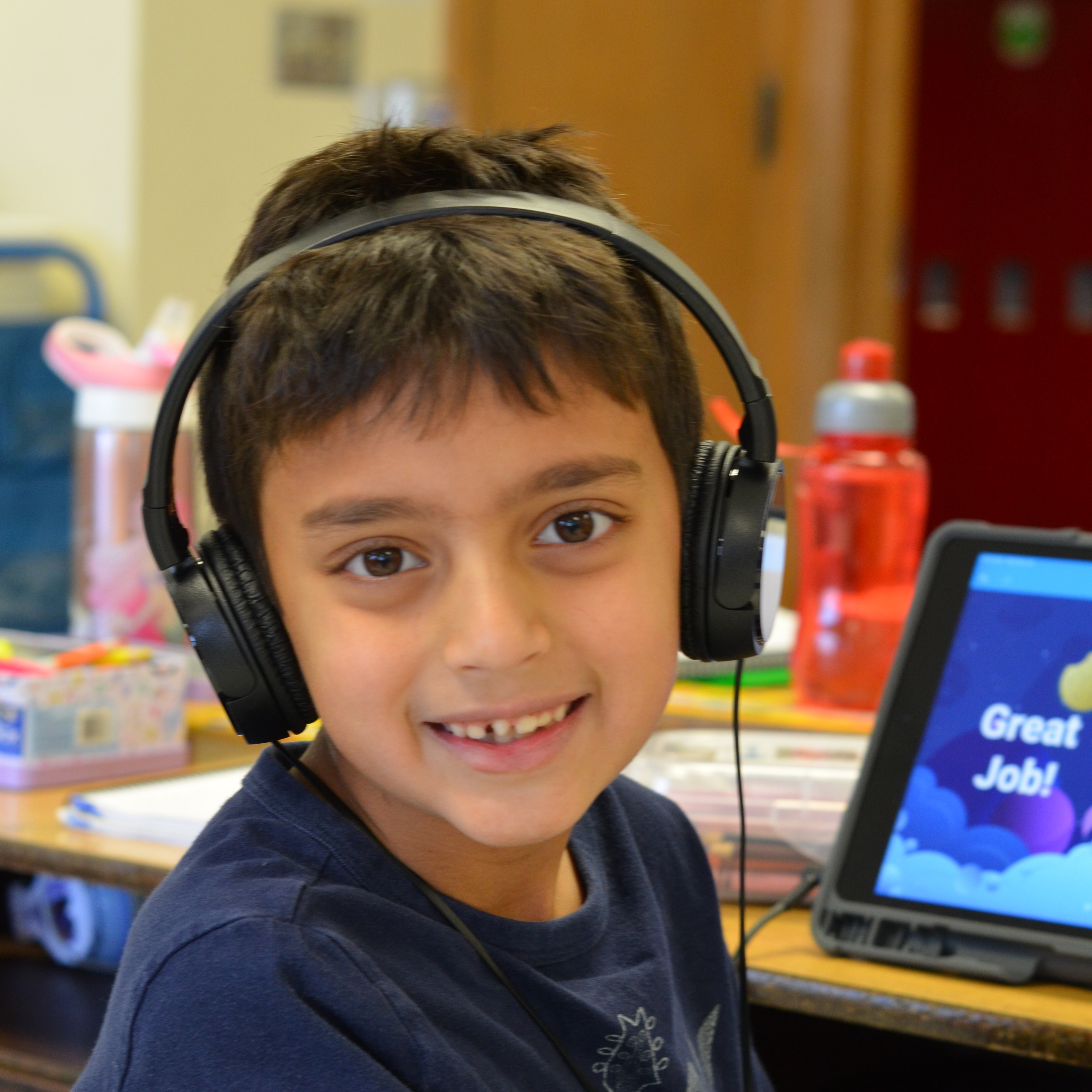 A student with headphones on looking at the camera
