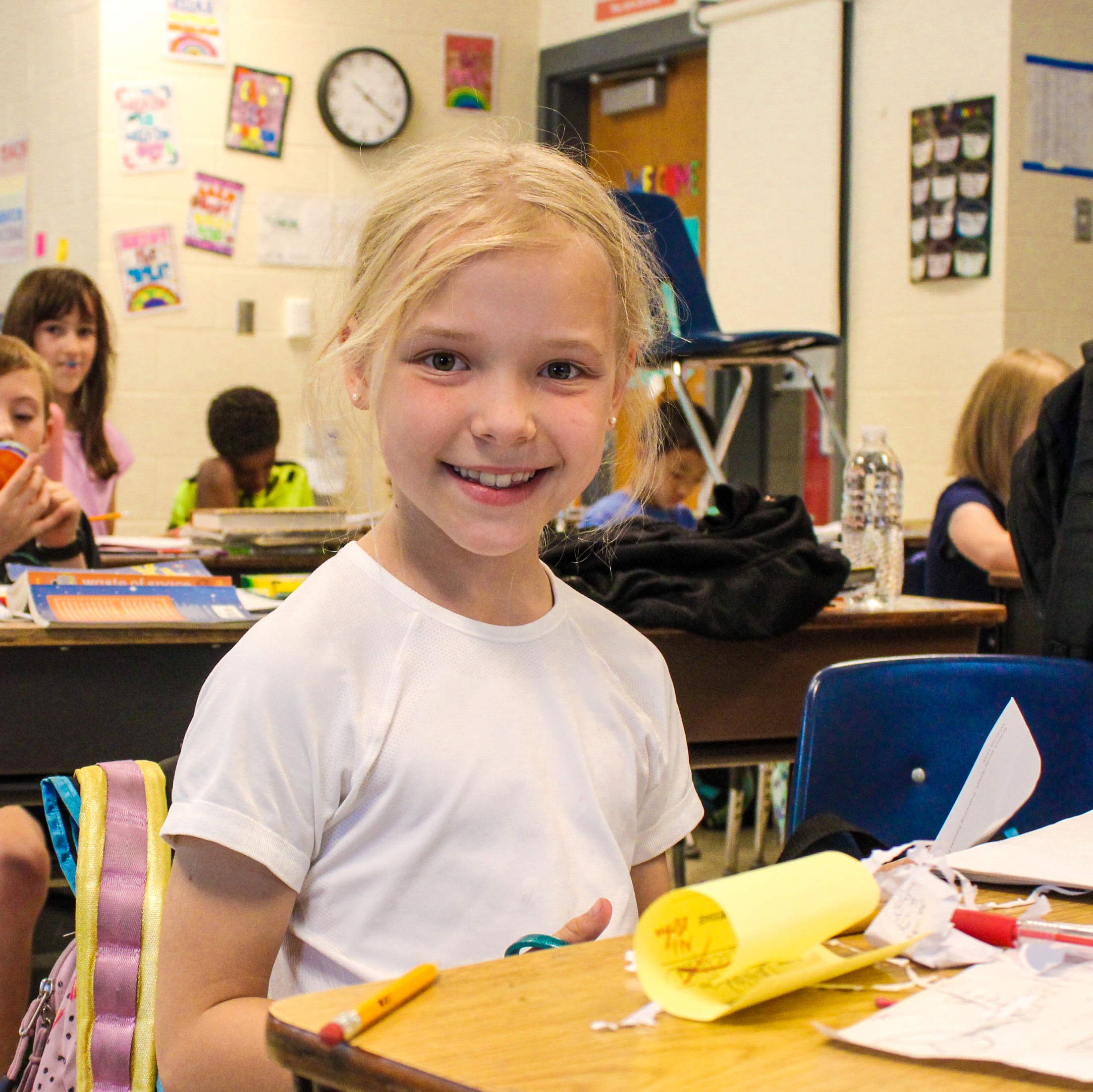 A student sitting at a desk, smiling at the camera