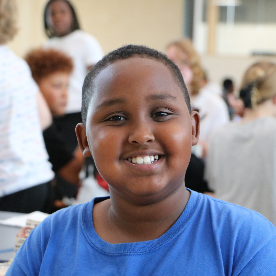 Student smiling at the camera while sitting at a cafeteria table