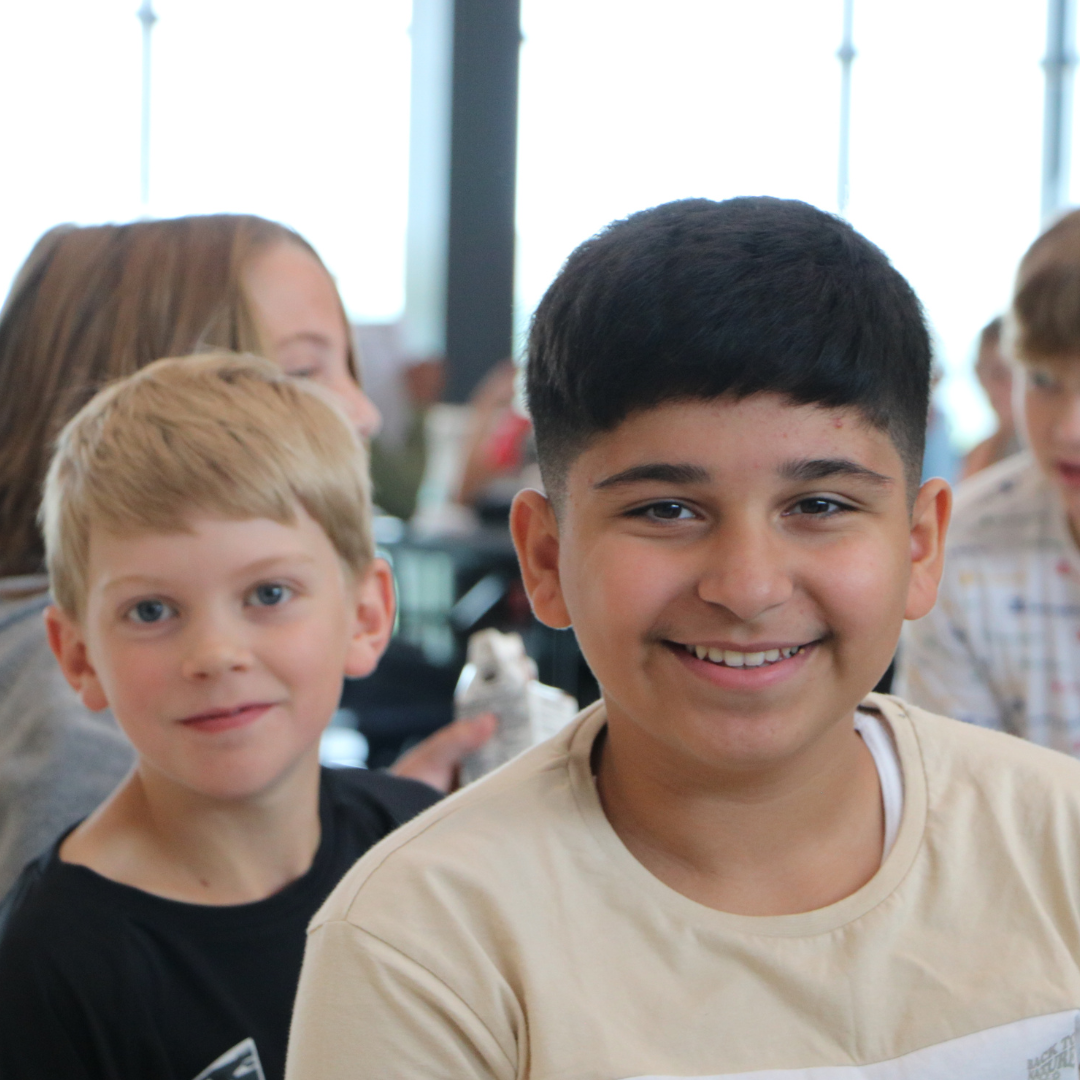 Two students in class smiling at the camera