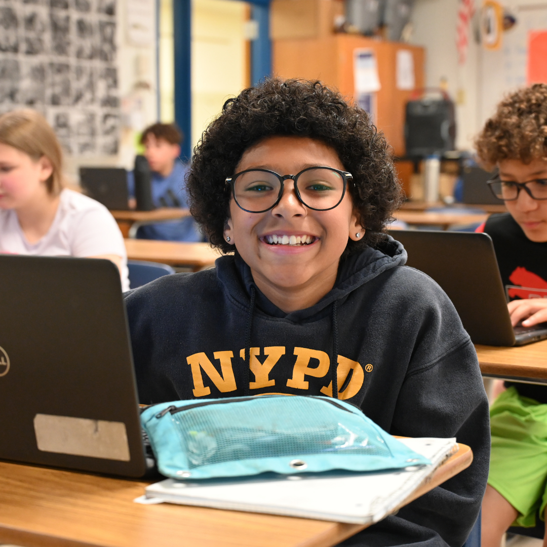 Student at desk smiling at the camera
