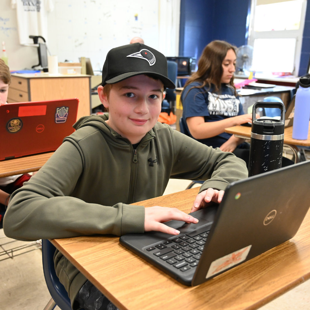 Student working on computer and smiling