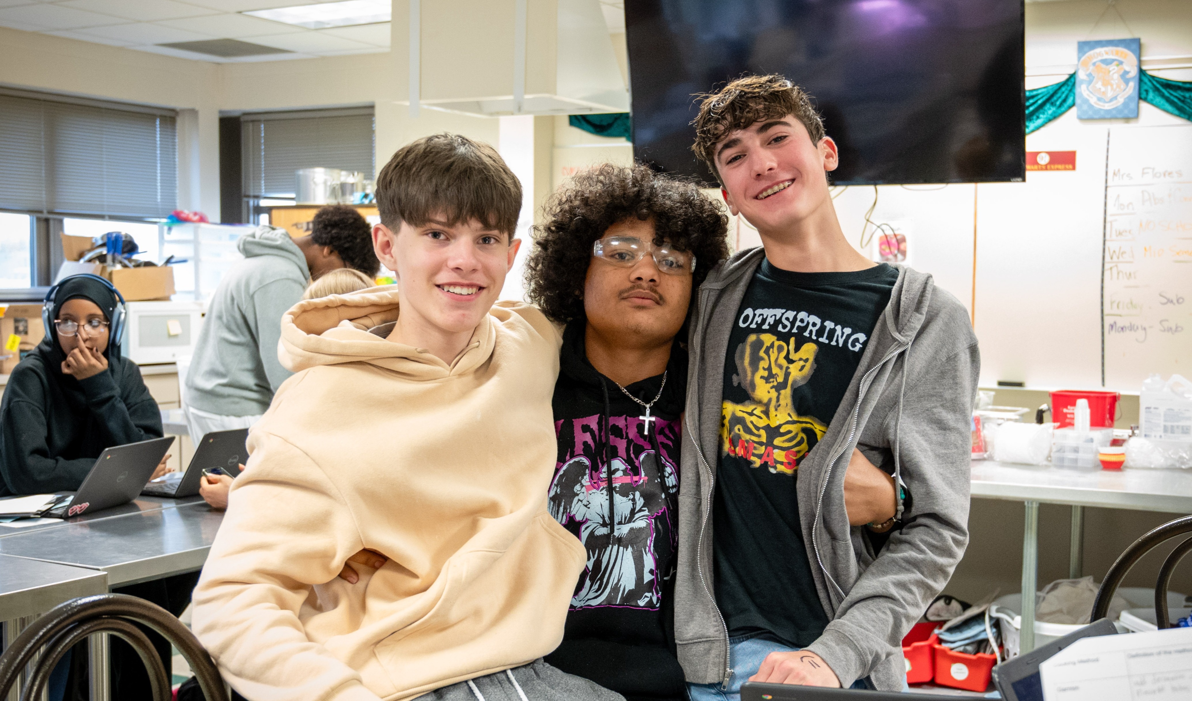 Three guys smile for the camera, arm in arm.