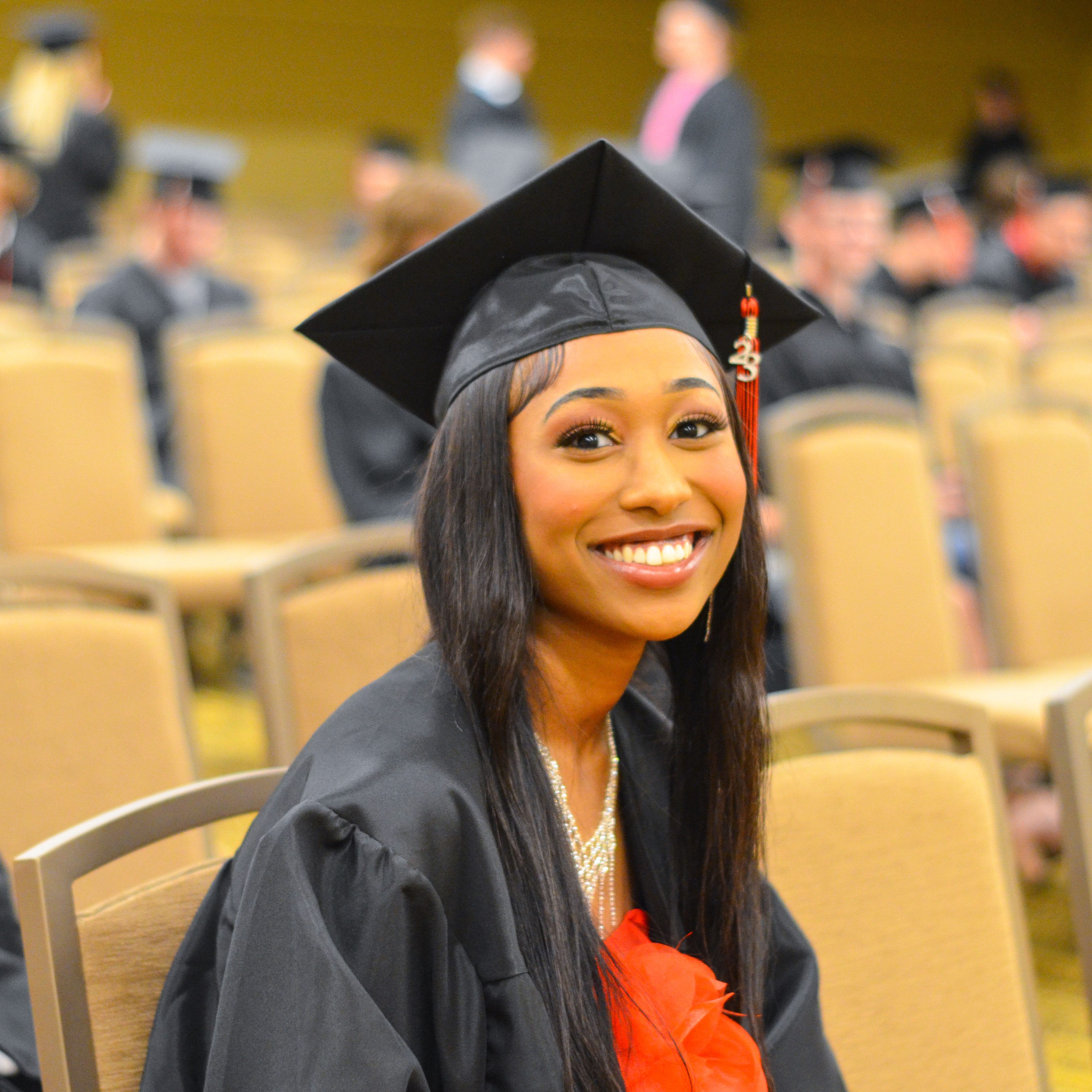 A recent graduate in her cap and gown, smiling at the camera