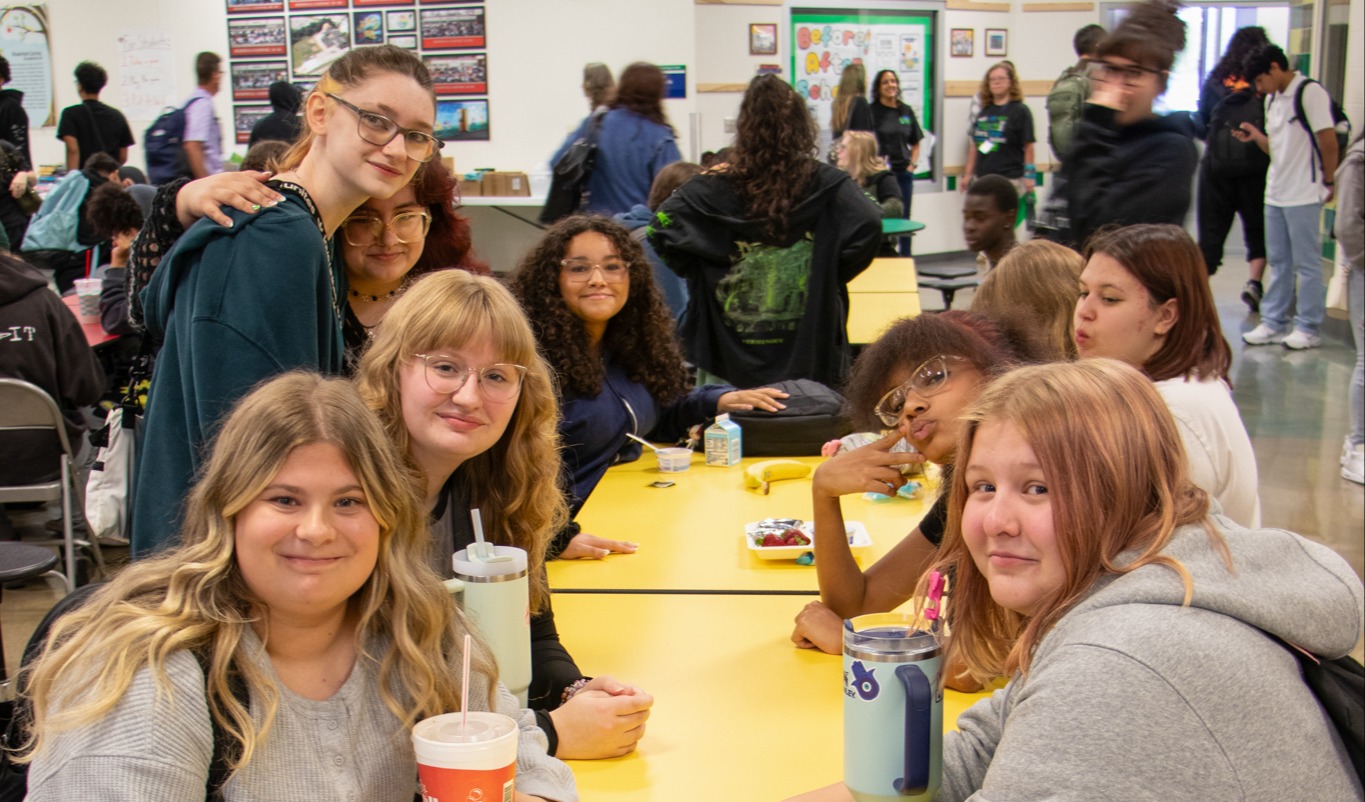 Students in the cafeteria smiling at the camera