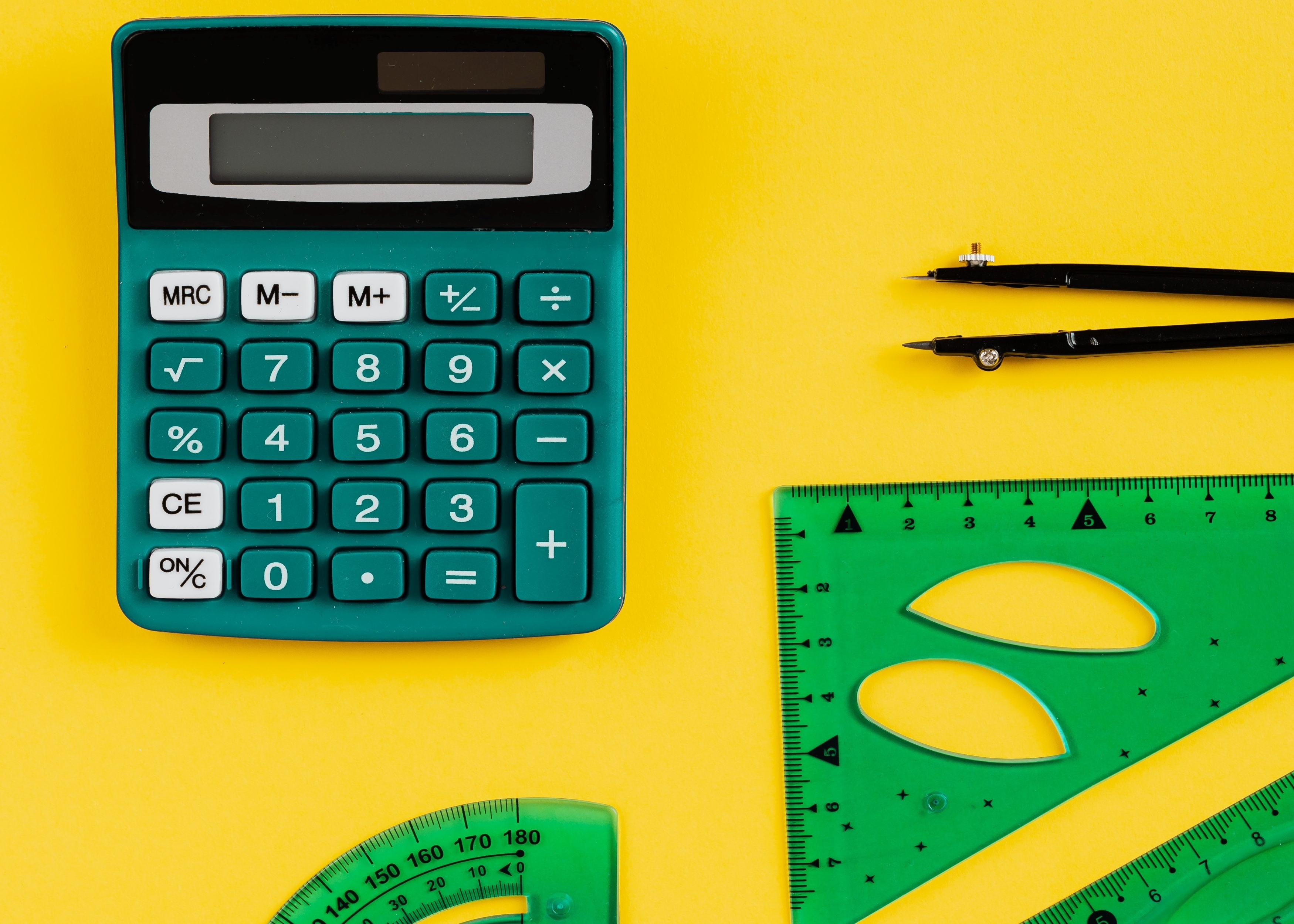 calculator and protractors scattered over a yellow background