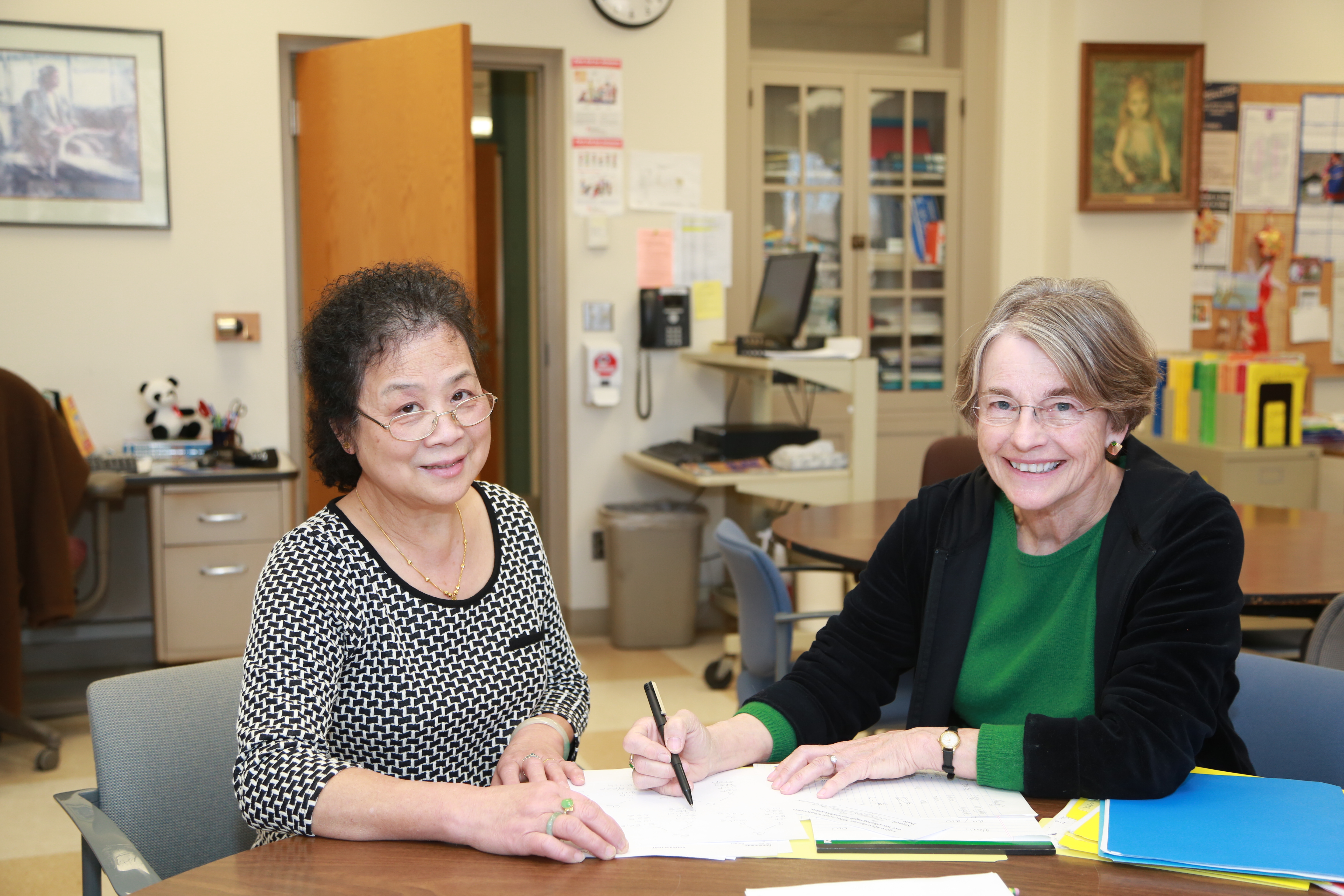 2 woman looking at the camera while working on notes at a table