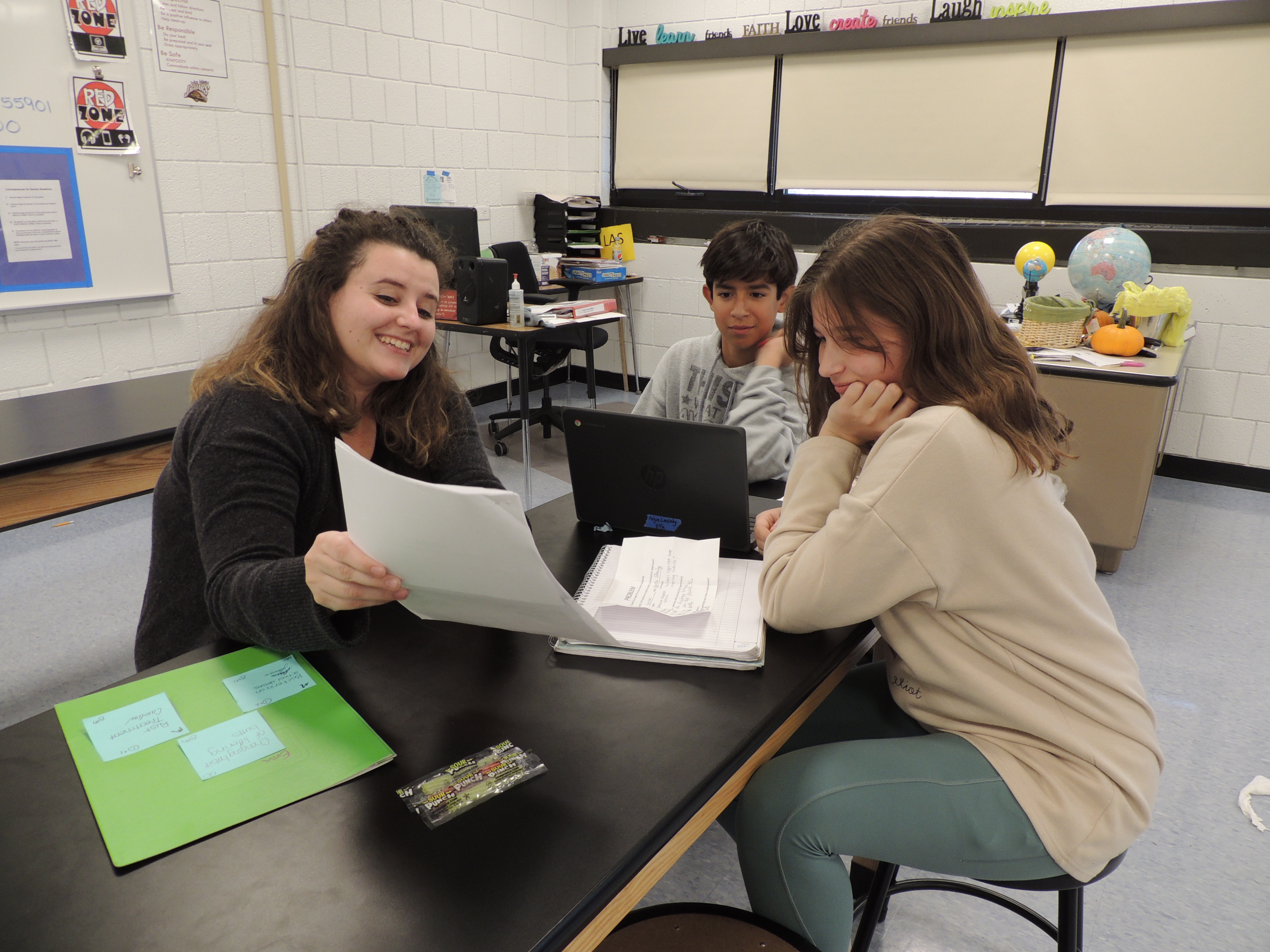 smiling mentor showing document to two students