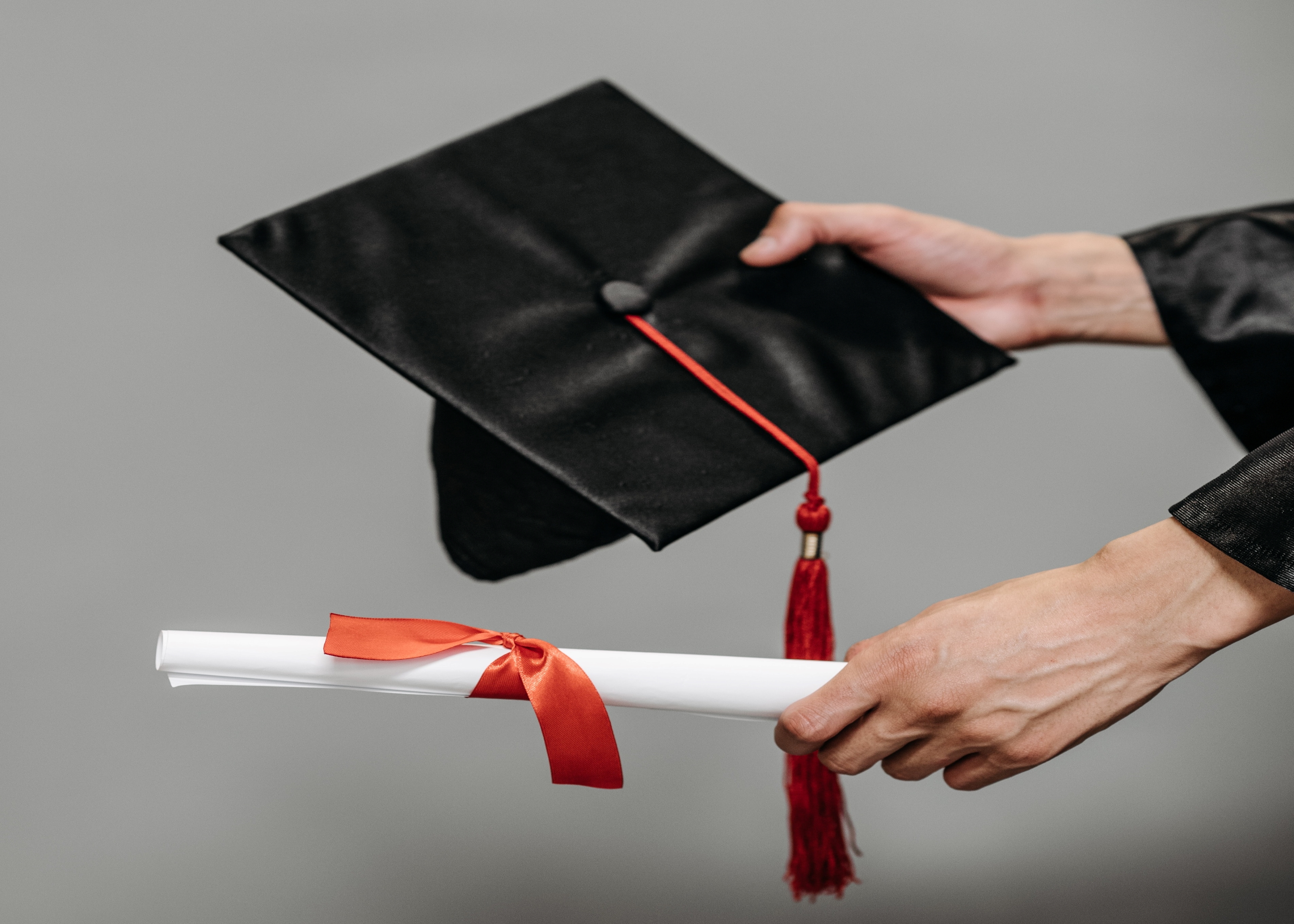 person handing over a cap and diploma