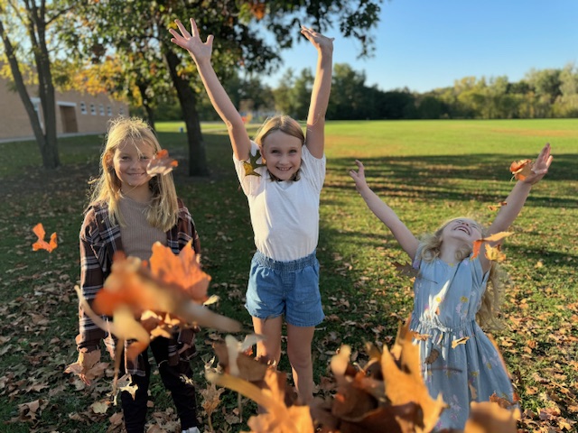 children in a pile of leaves jumping
