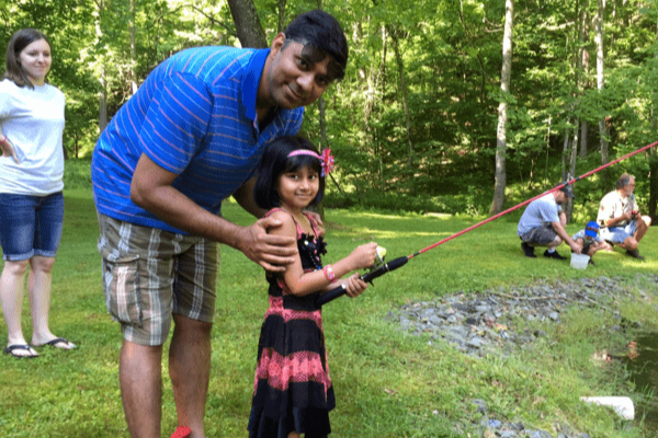 father and daughter on bank of pond, daughter has fishing rod in hand