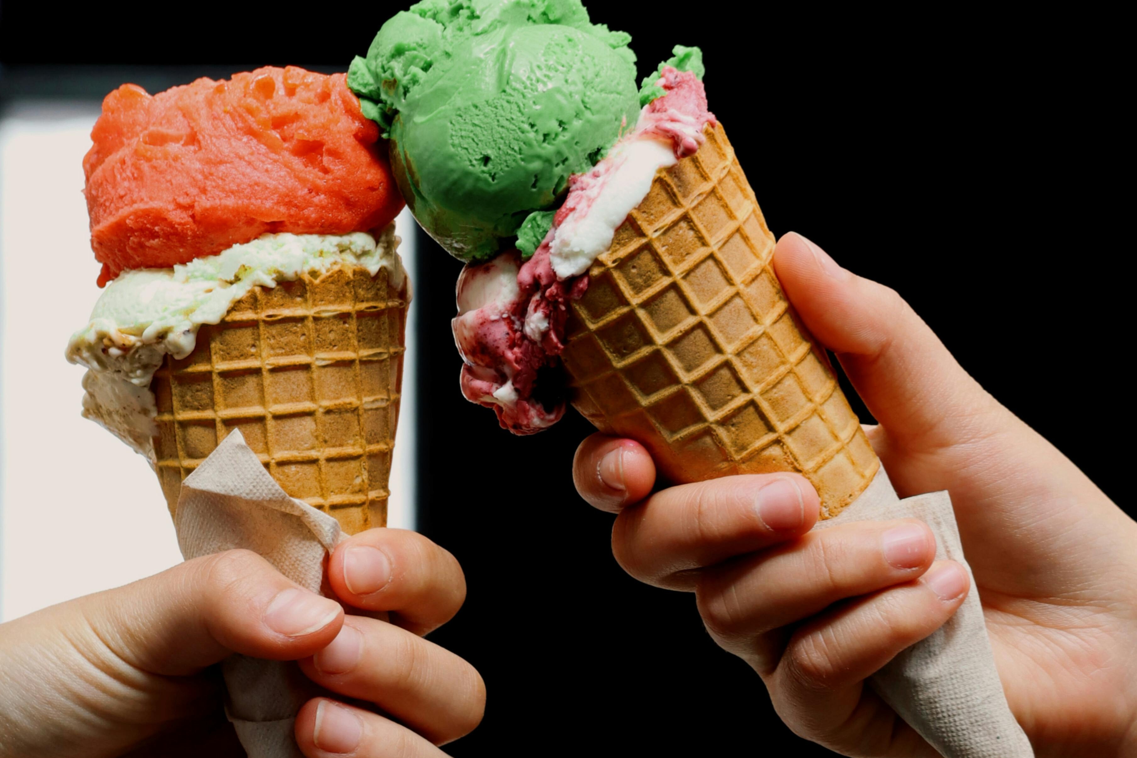 two ice cream cones being tapped together like clinking glasses