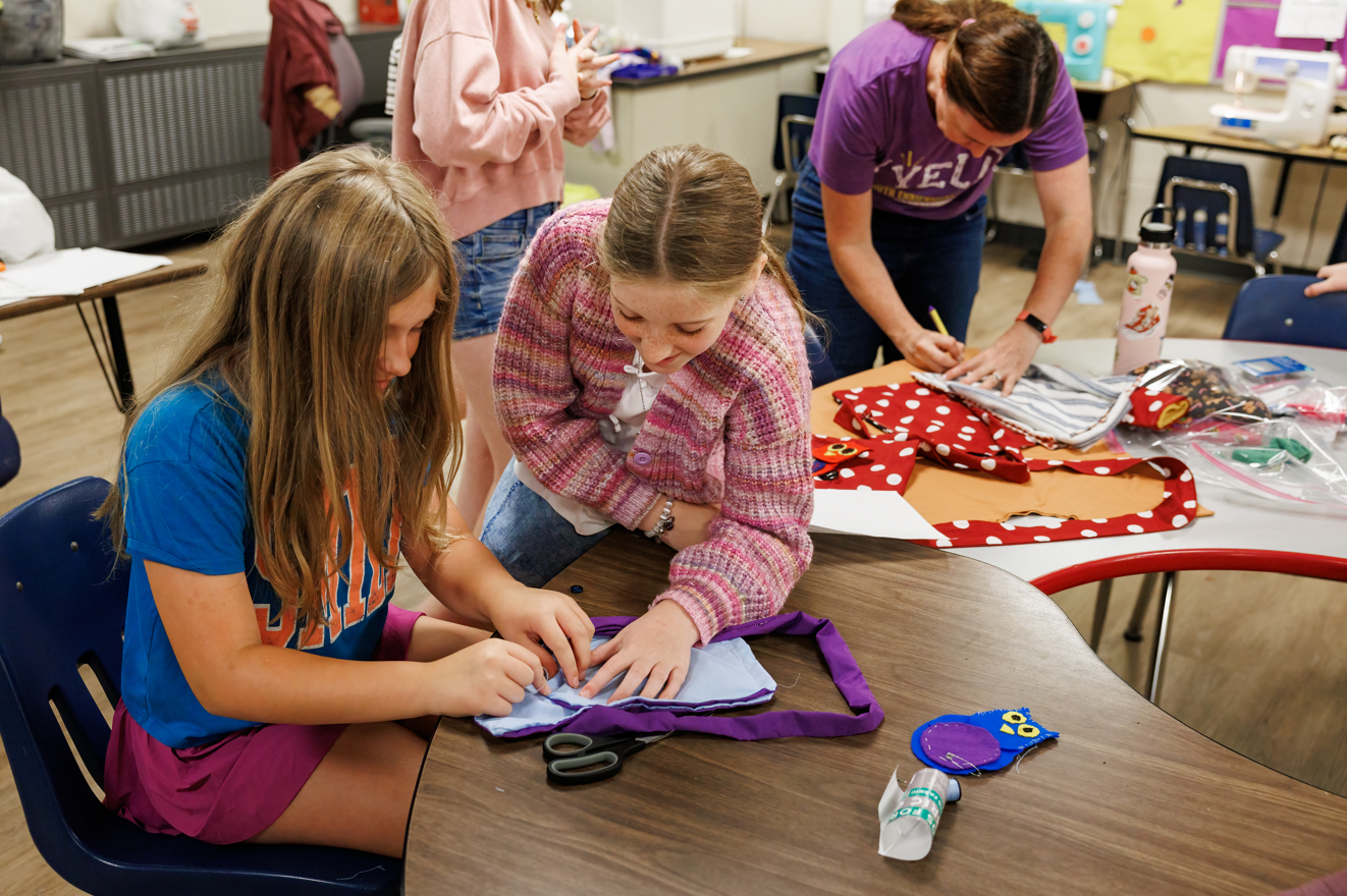young girls working together to sew a handbag