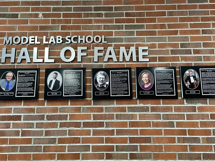 Model Lab school hall of fame.  5 photo plaques hanging up on a brick wall