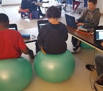 students on chromebooks while sitting on exercise ball
