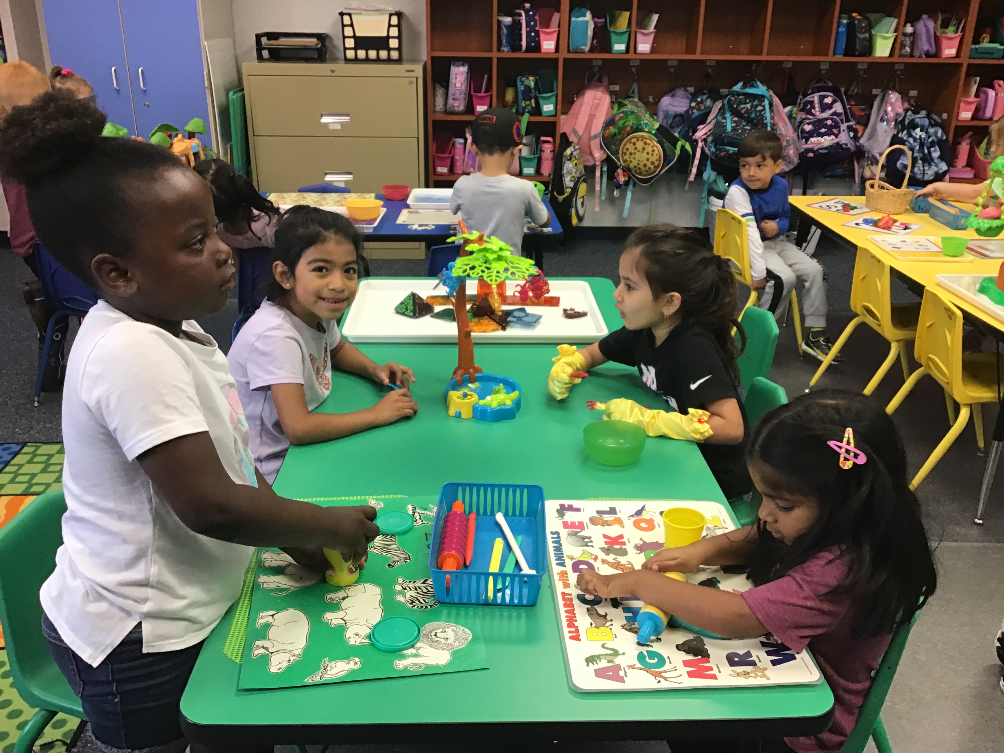 Students playing with play doh and two students playing a monkey board game.