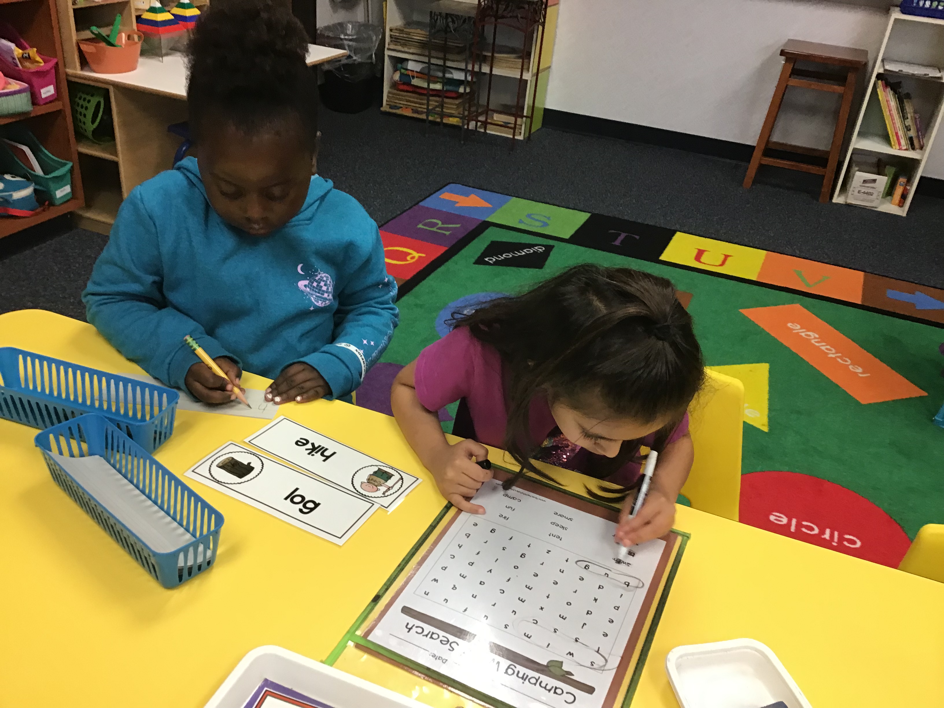 Two students writing camping words and completing a word search.
