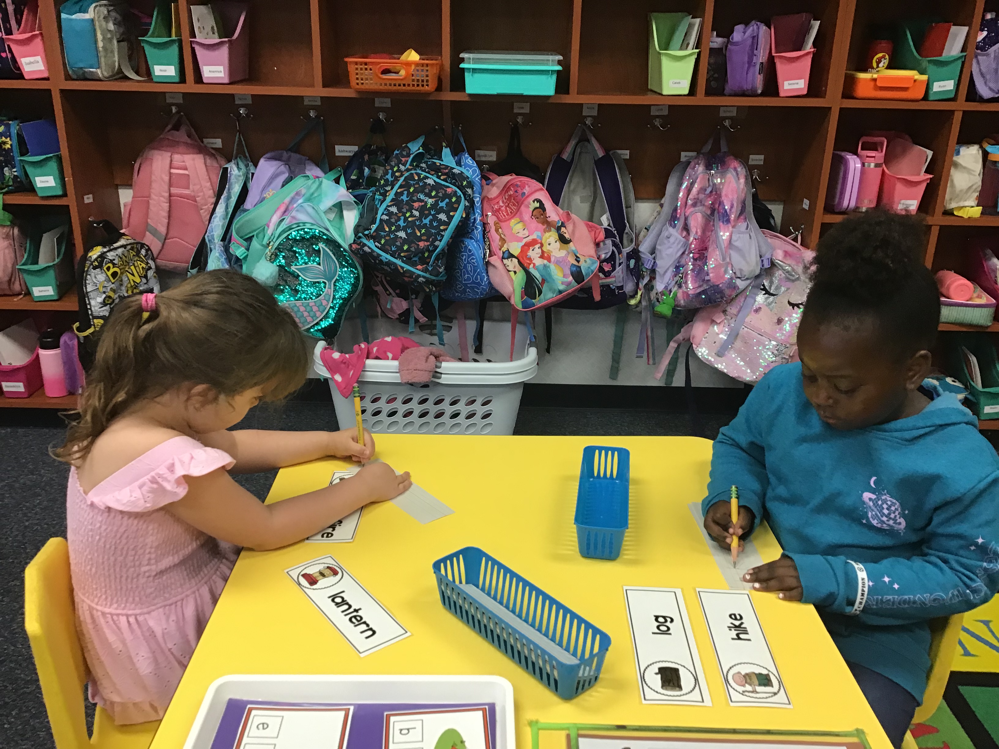 Two students at the phonics table writing two camping words.