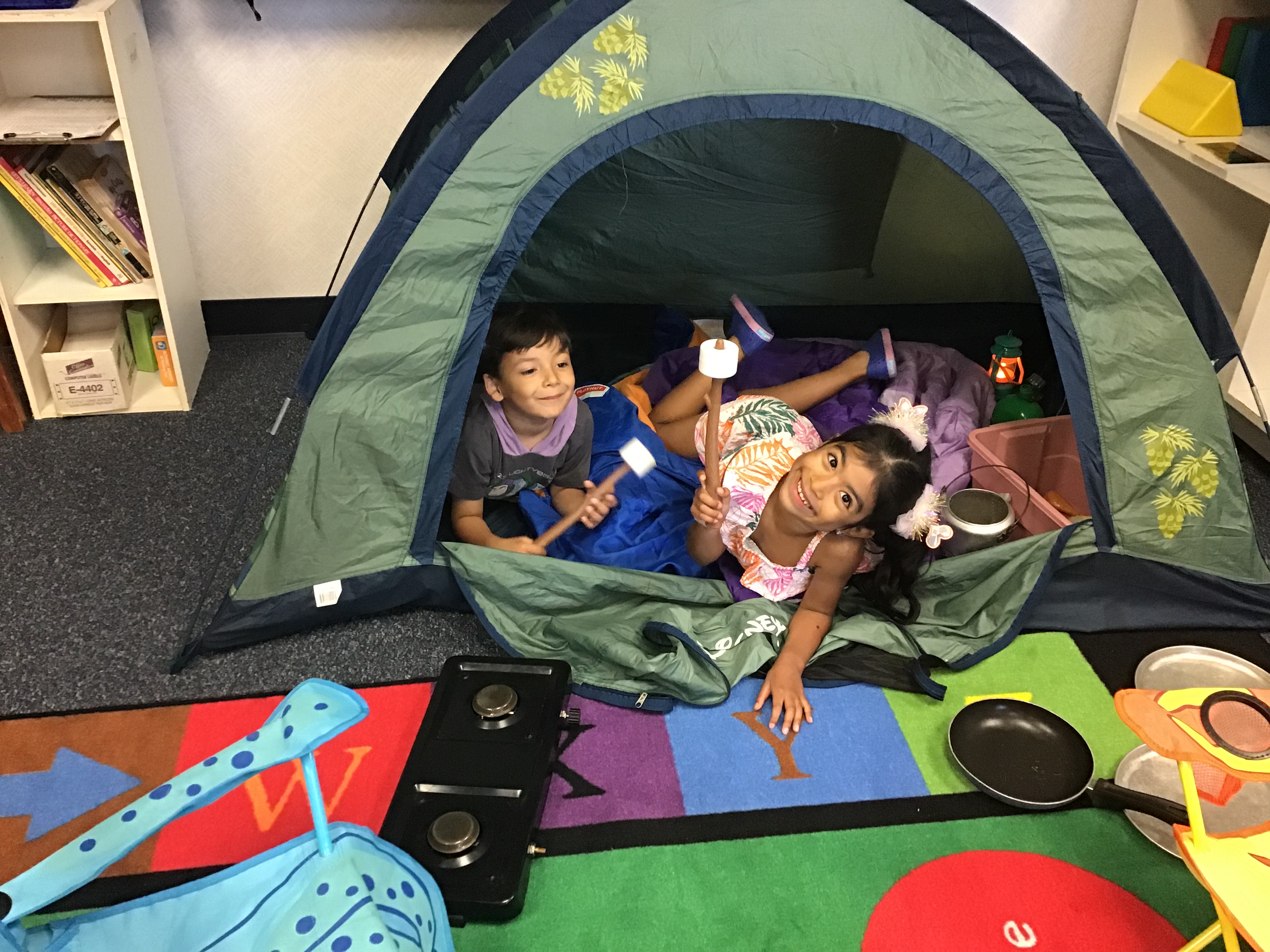 Two students playing in the tent and making smores.