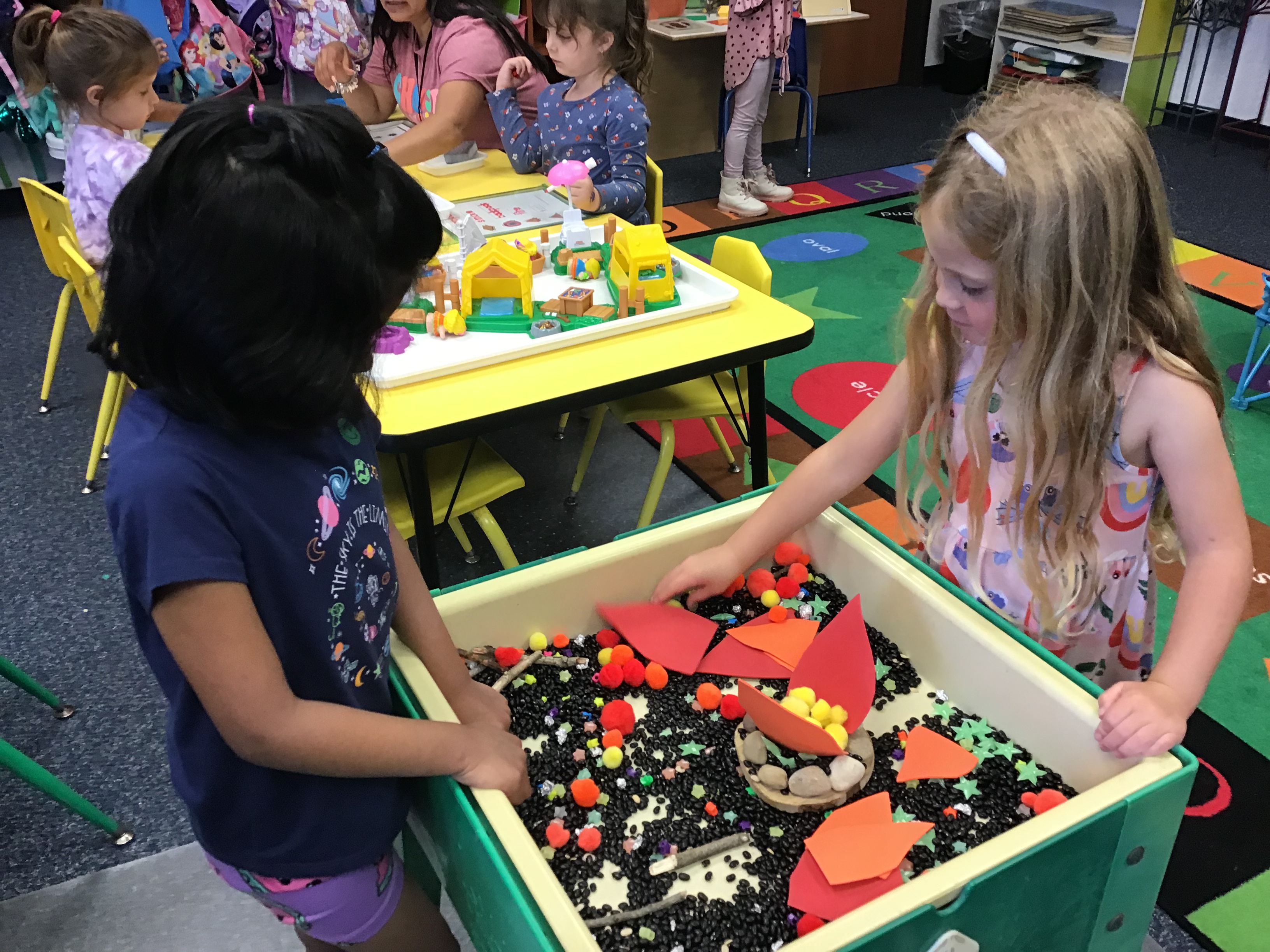 Two students playing at the sensory table with pretend camp fire.