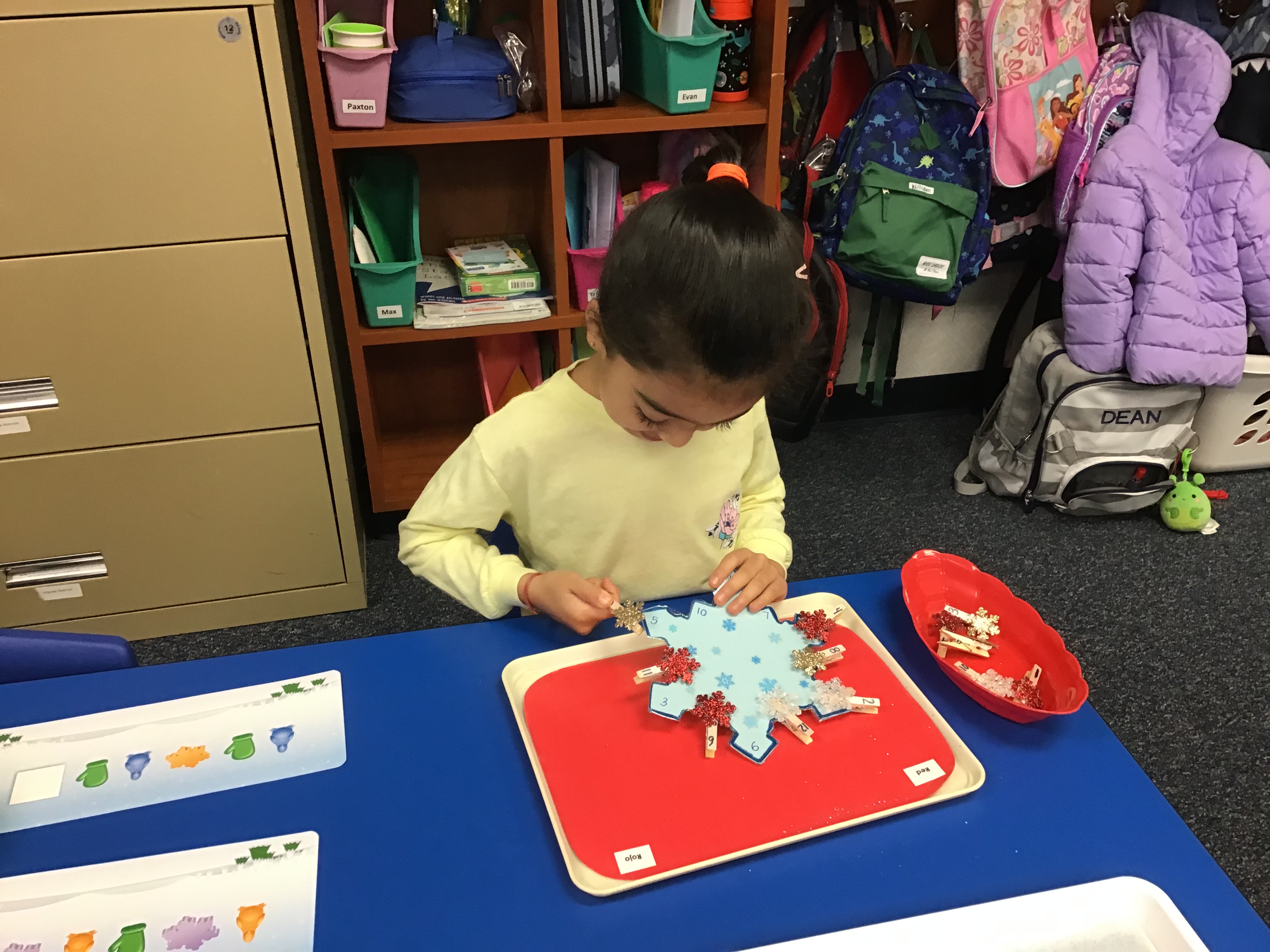 Student matching snowflakes to large numbered snowflake with clothespin