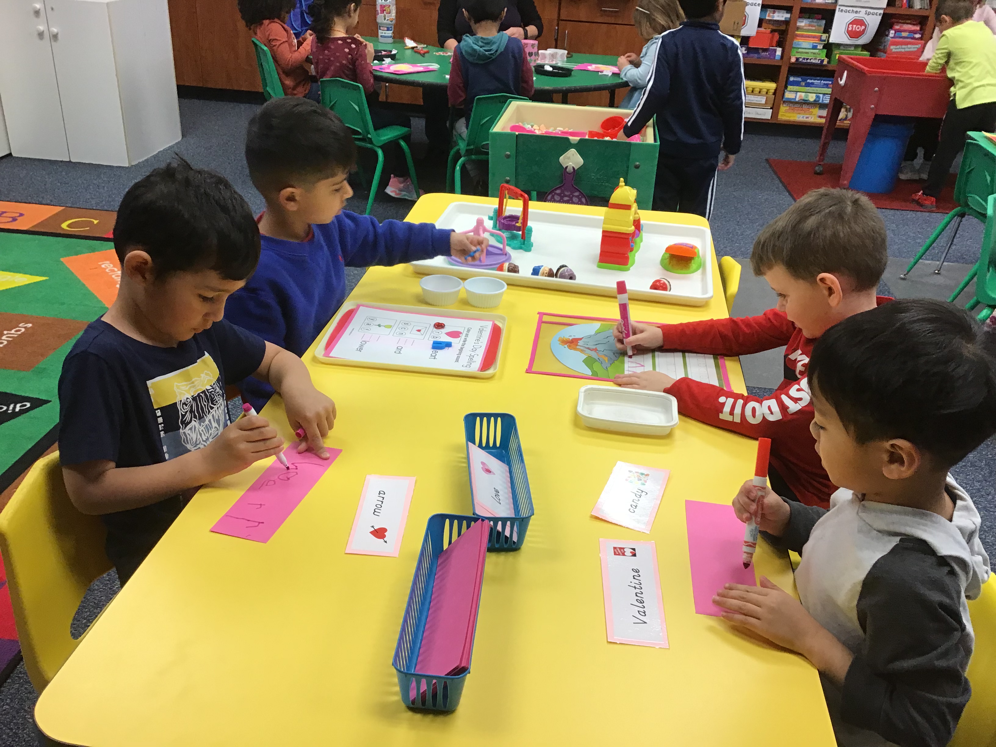 Students at the phonics table writing two words for Valentine theme