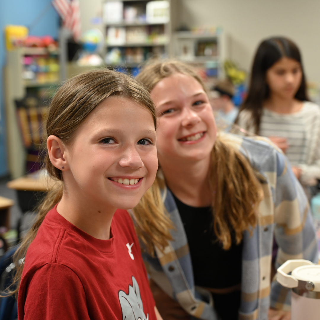 Image of two female students working together on smiling at the camera