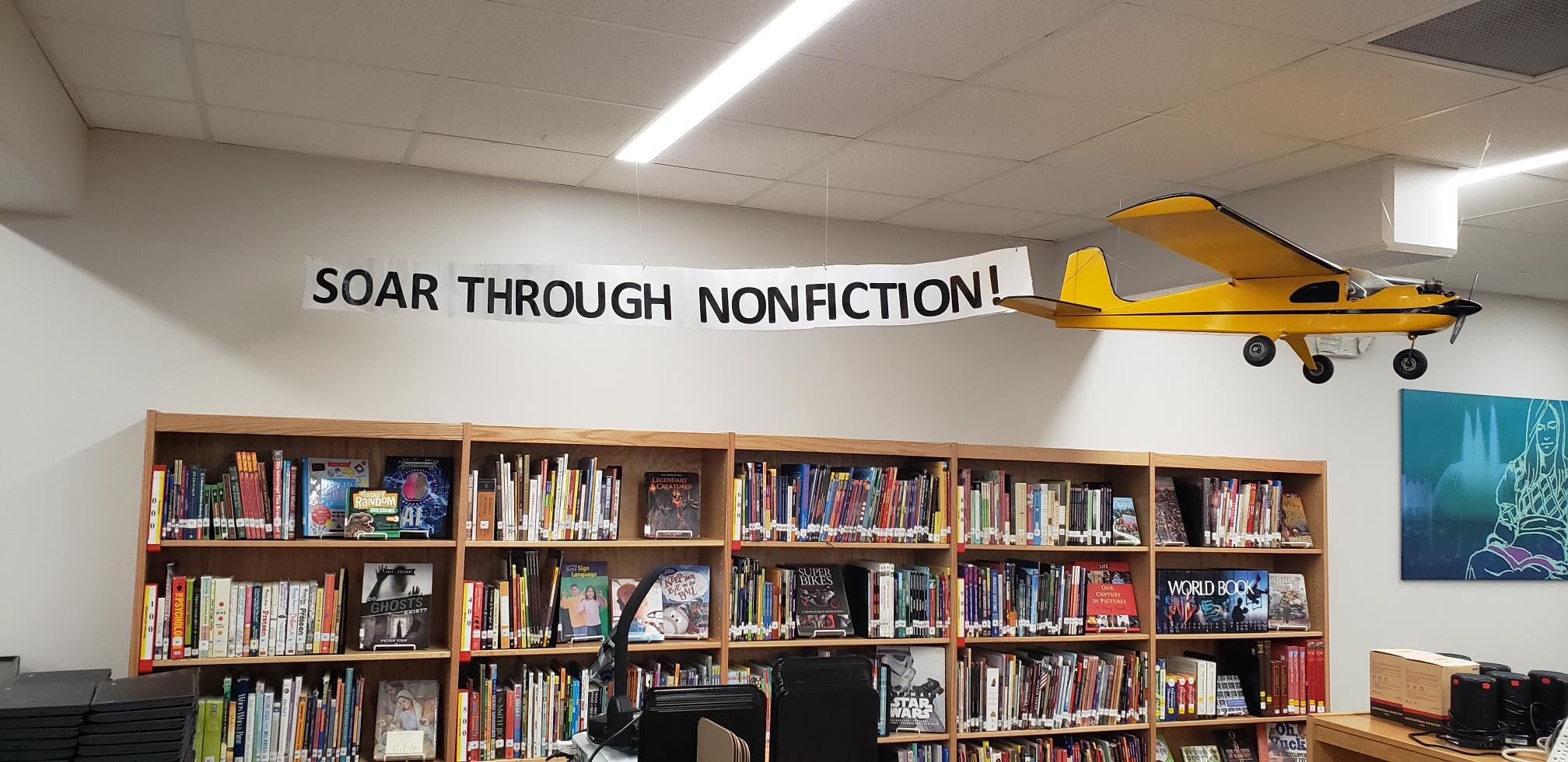 books with an airplane and tail tag that says Soar Through Nonfiction!