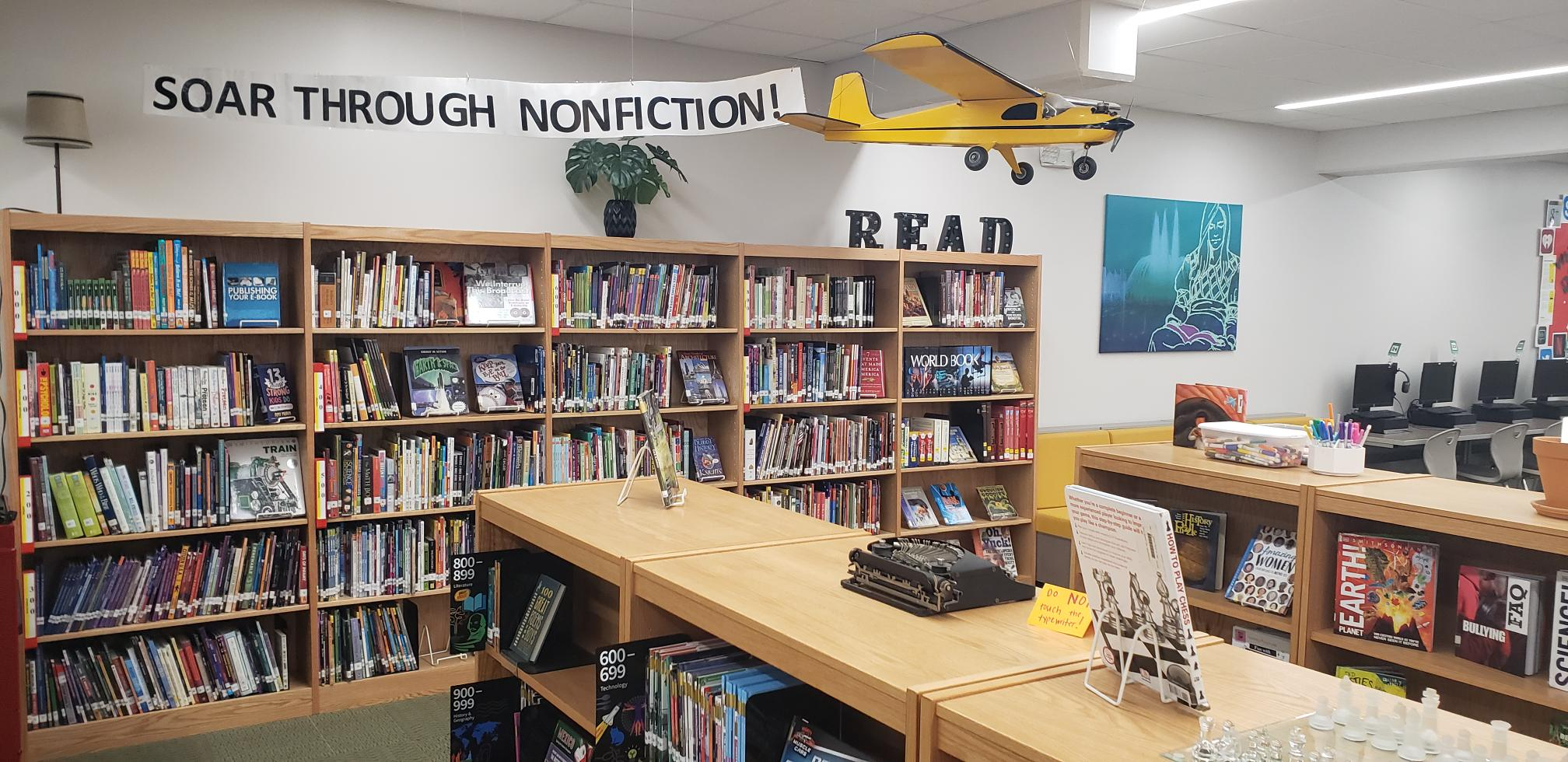 books with an airplane and tail tag that says Soar Through Nonfiction!