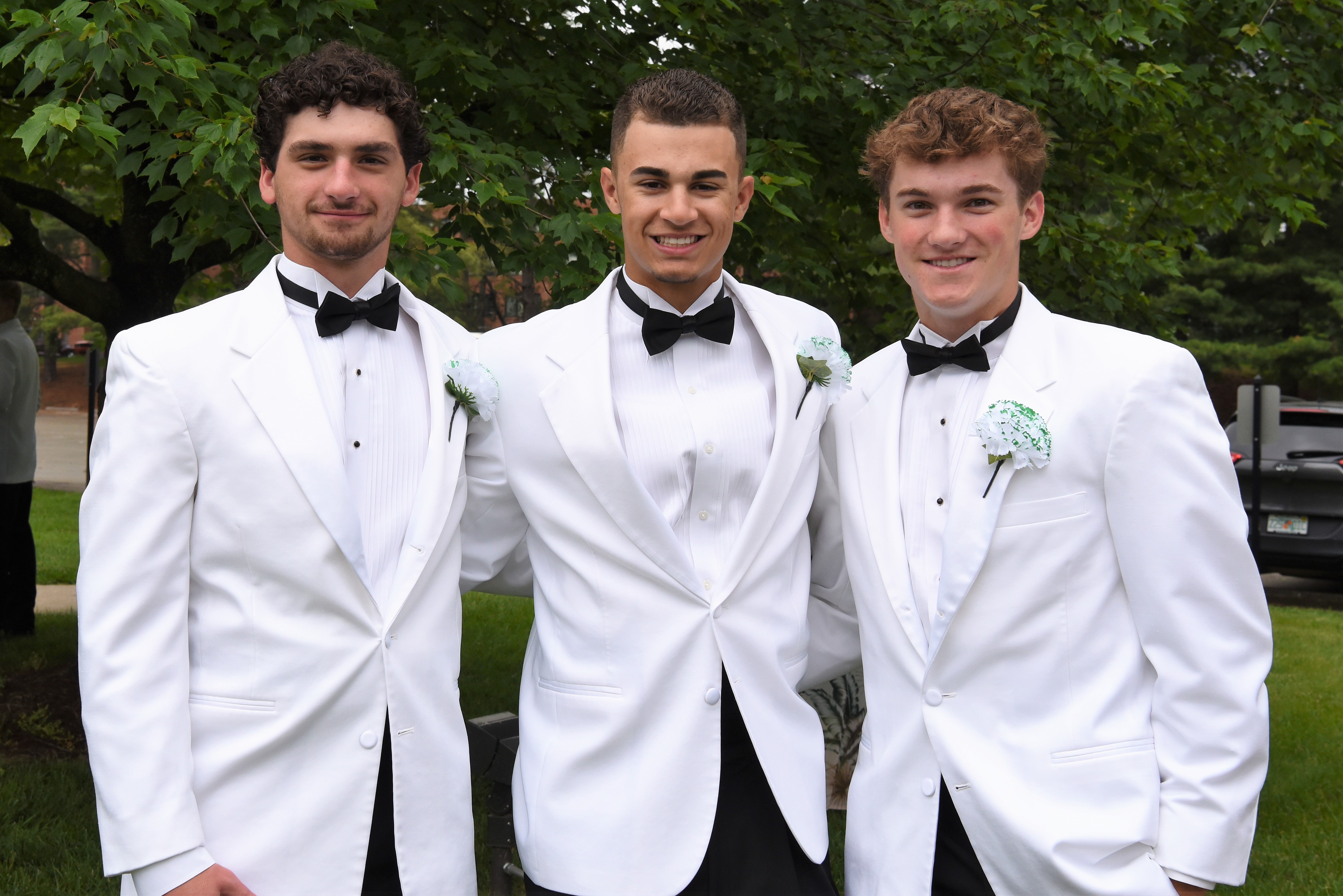 3 students standing with white suits on