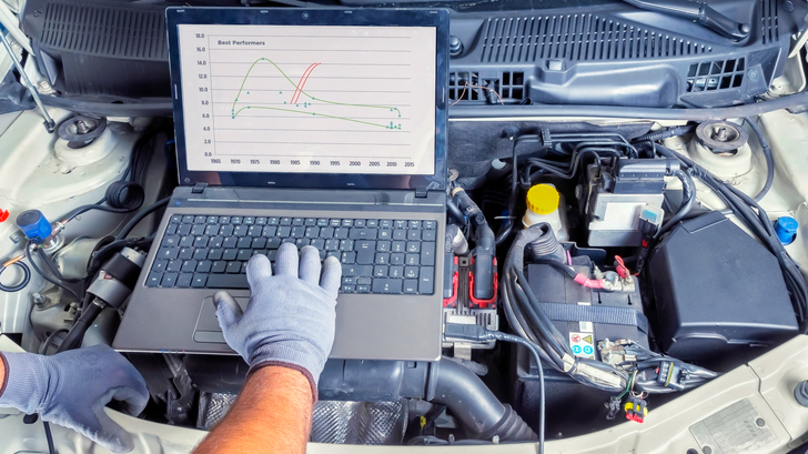 person checking car engine with computer