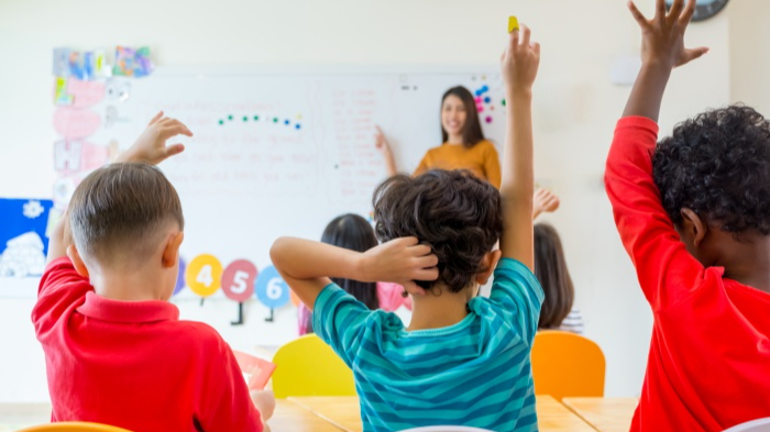 children in class with arms raised
