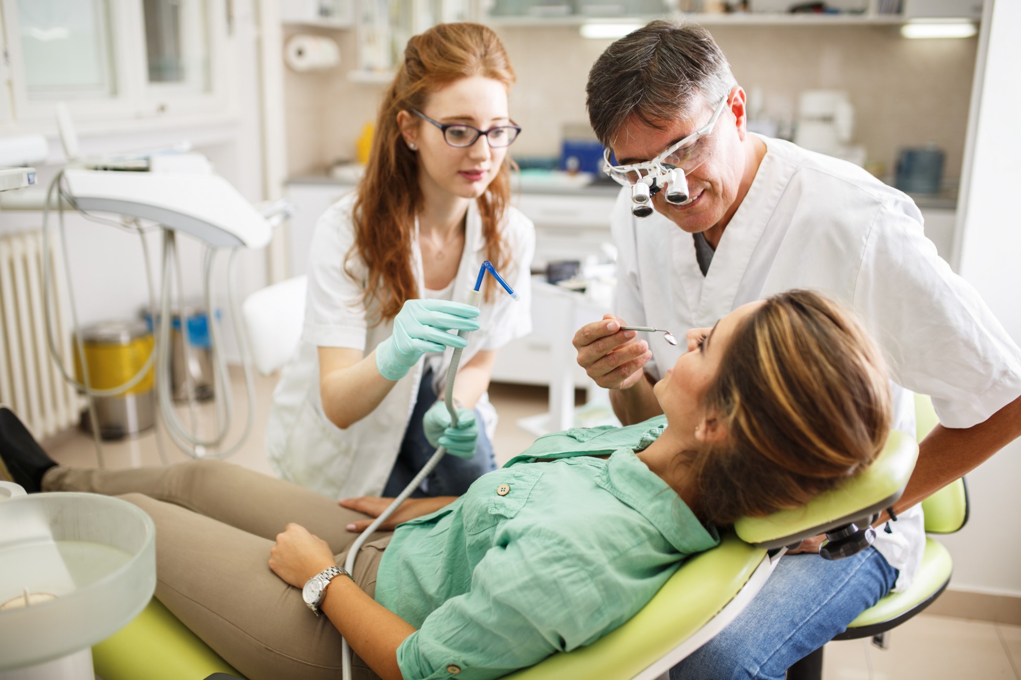 Woman receiving dental assistance from two other.