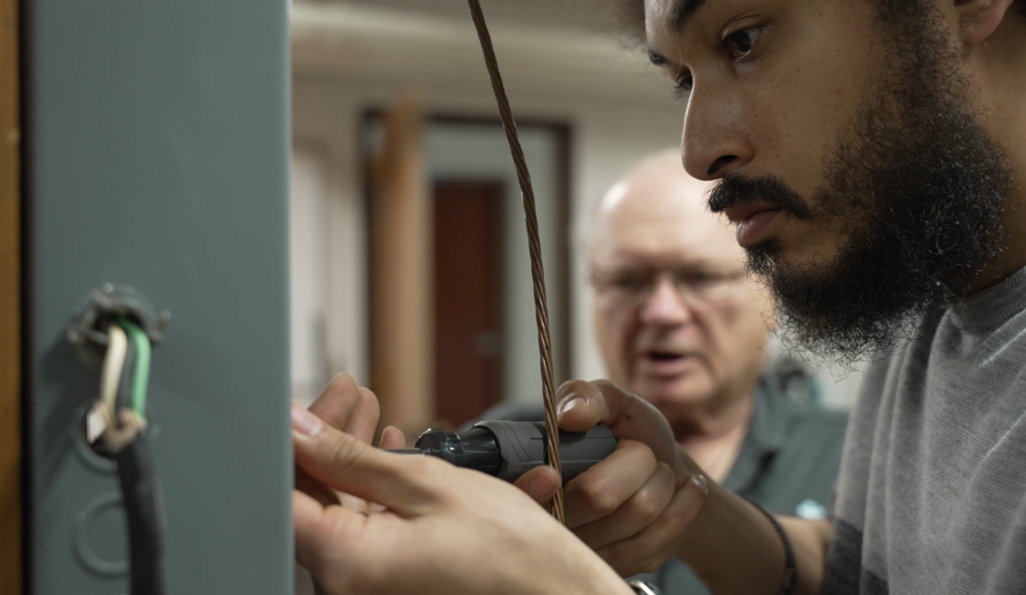 Two men working on a electric panel chatting