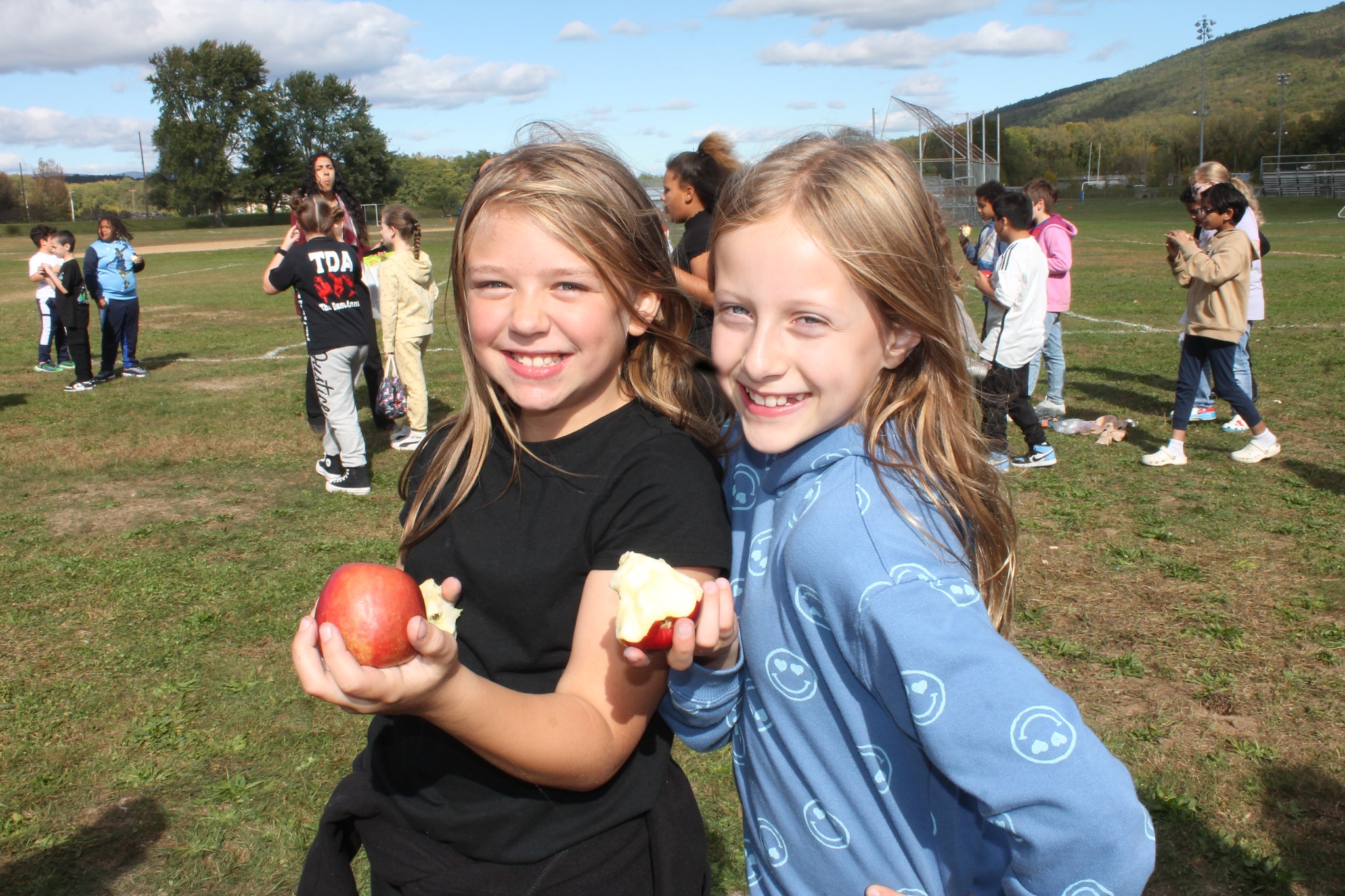 Two students smiling and holding apples