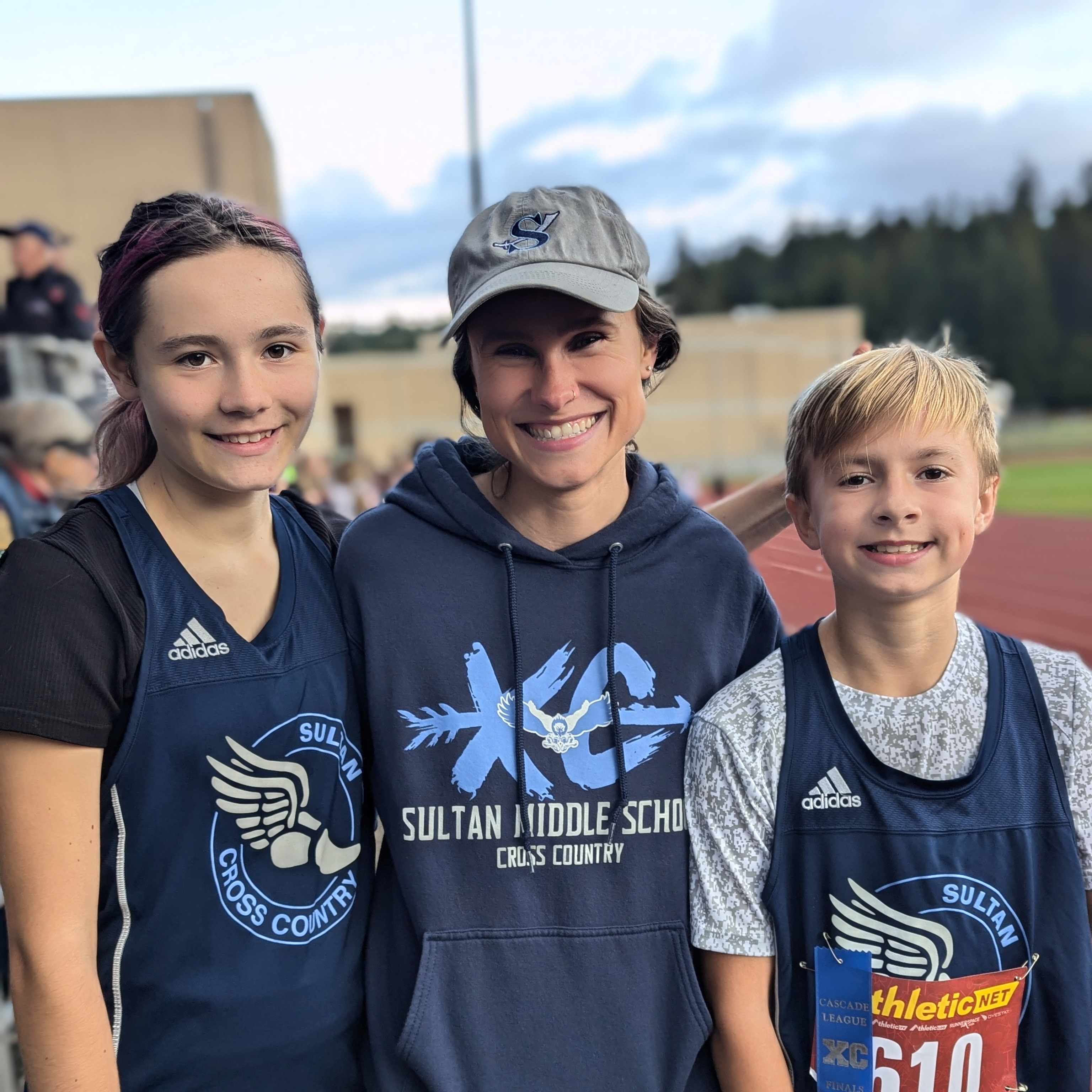 2  cross country runners posing with coach