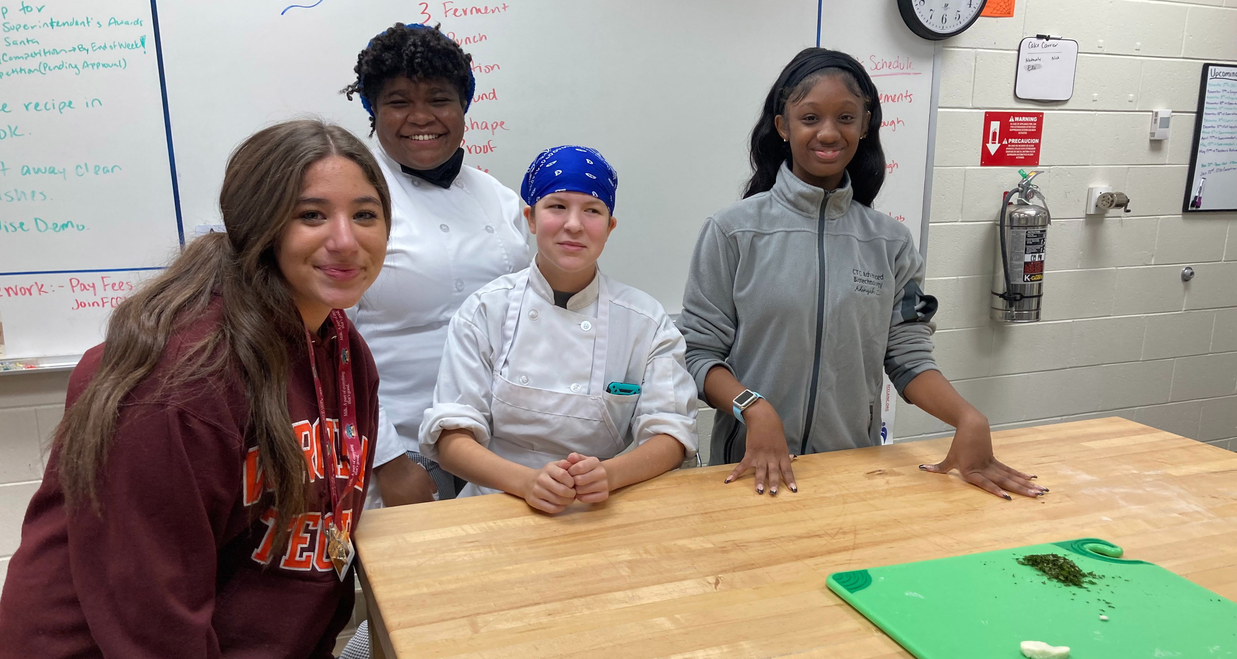 A culinary teacher and three students pose for a photo