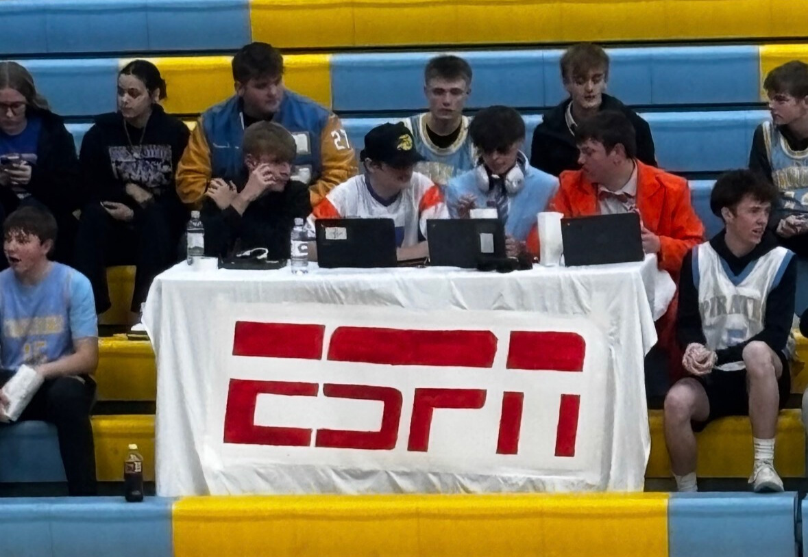 The student section has a table that says ESPN. The students are the commentators of the "show". They are dressed in suits