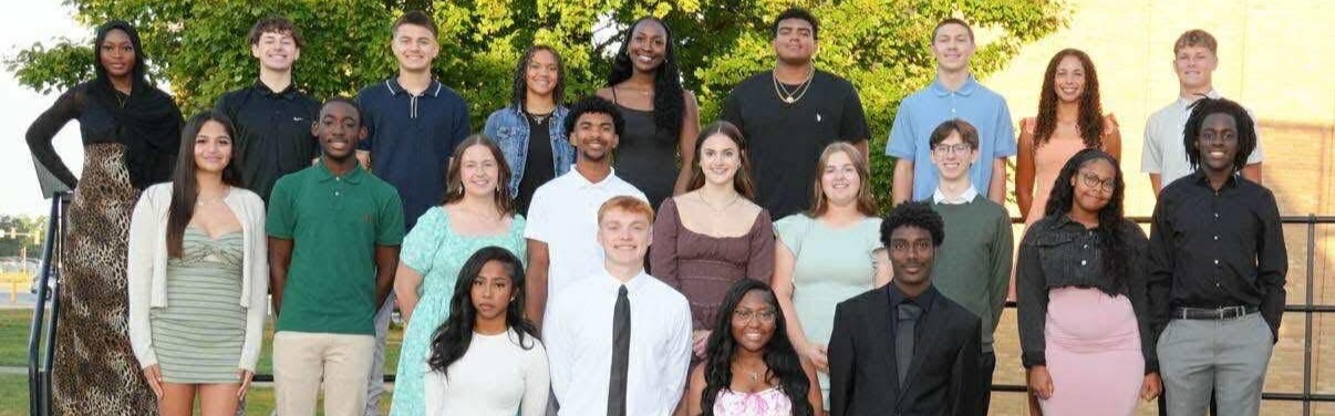 Homecoming court consisting of 10 teenage girls and 10 teenage boys. They were photographed outside on risers. A tree is in the background.