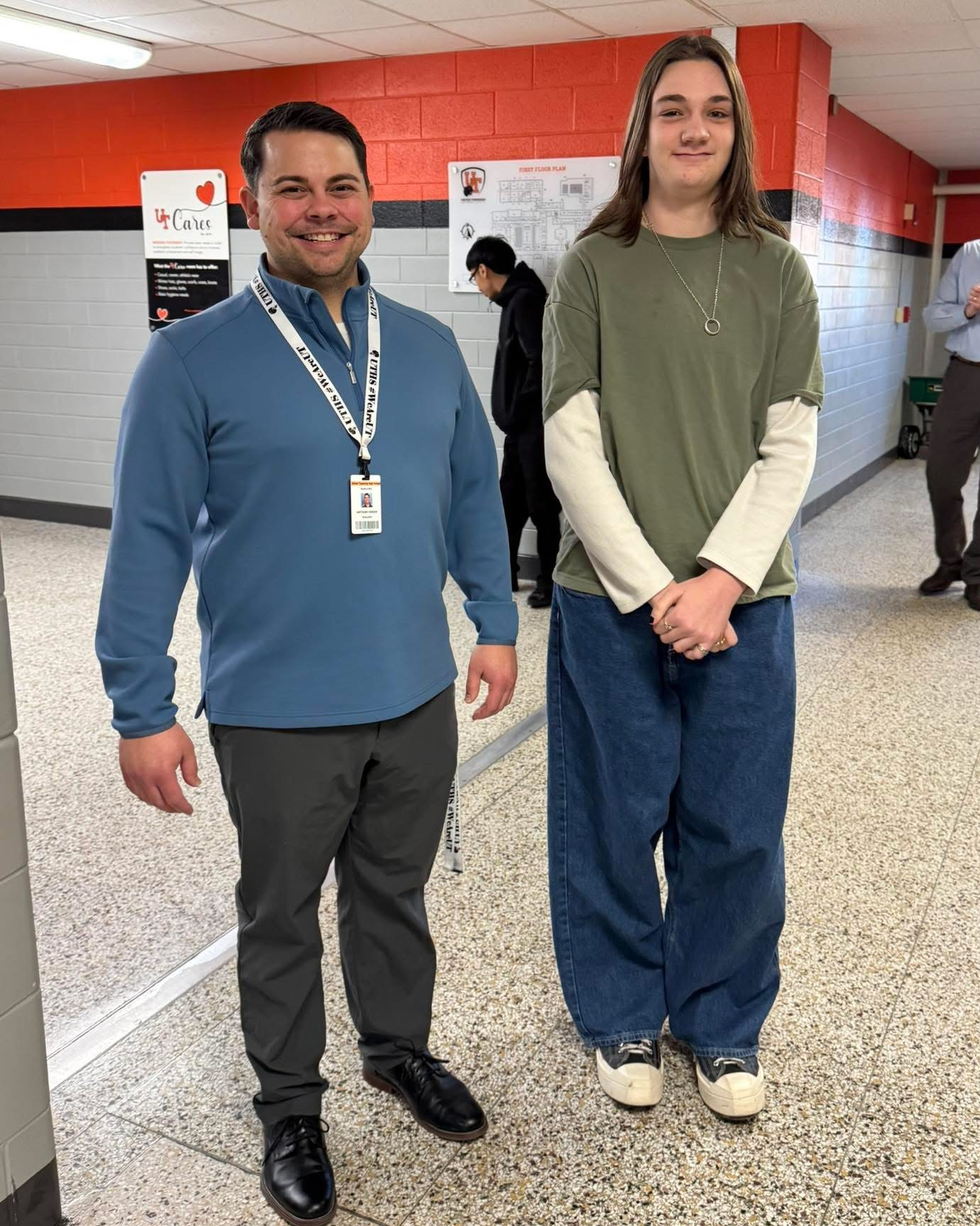 One staff member and one student in a hallway on walkthrough of the building to honor the student's achievement.